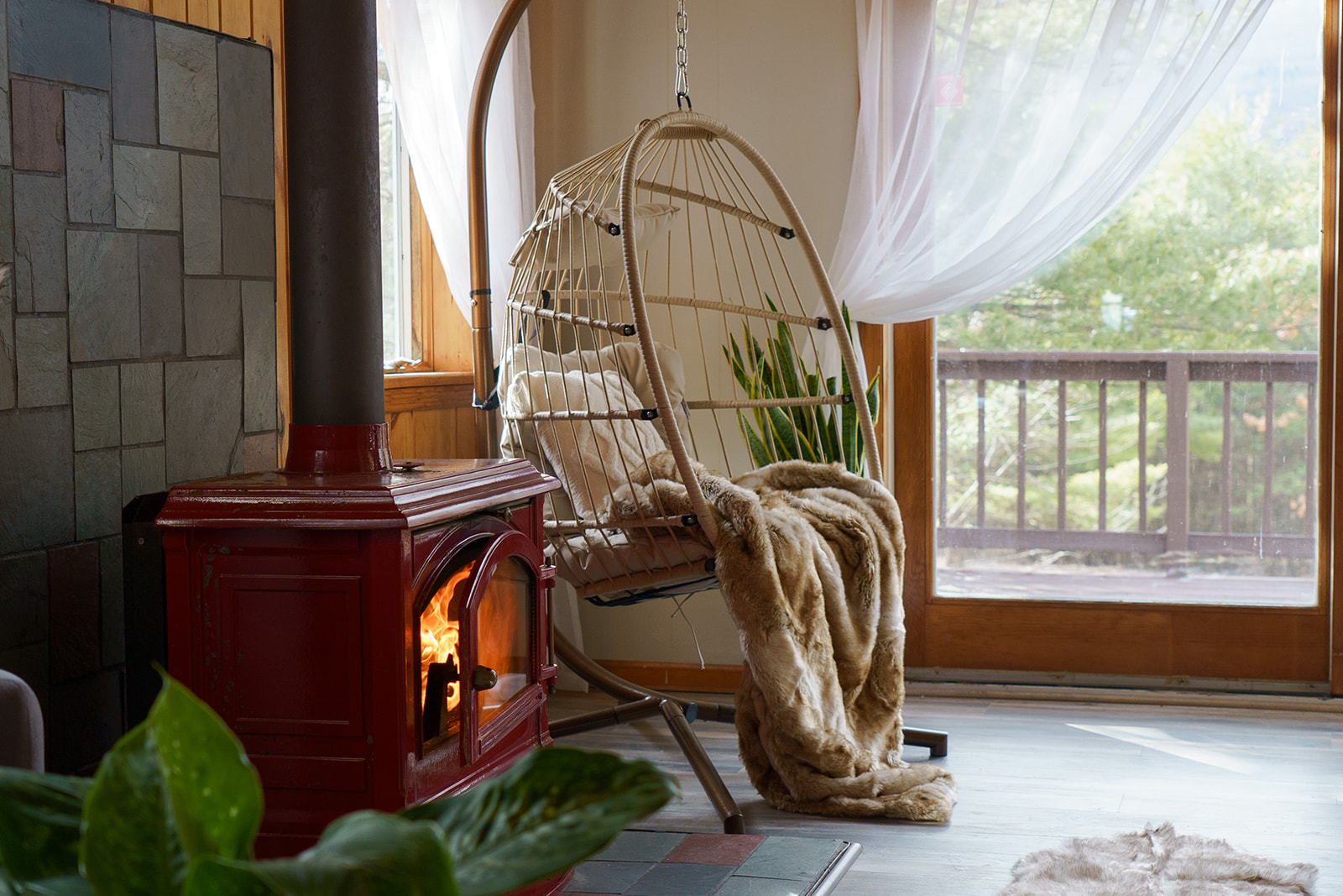 Cozy corner with hanging chair and wood stove