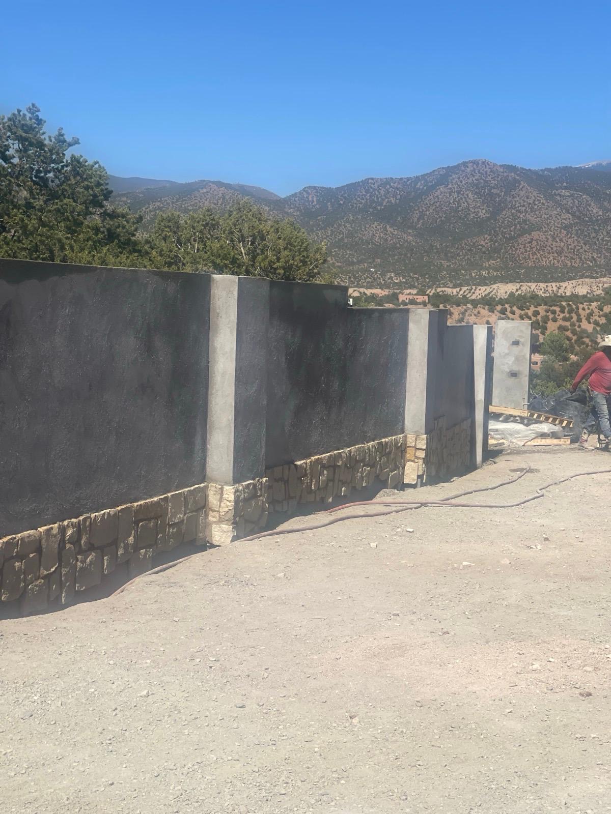 Exterior stucco walls with stone base and mountain backdrop