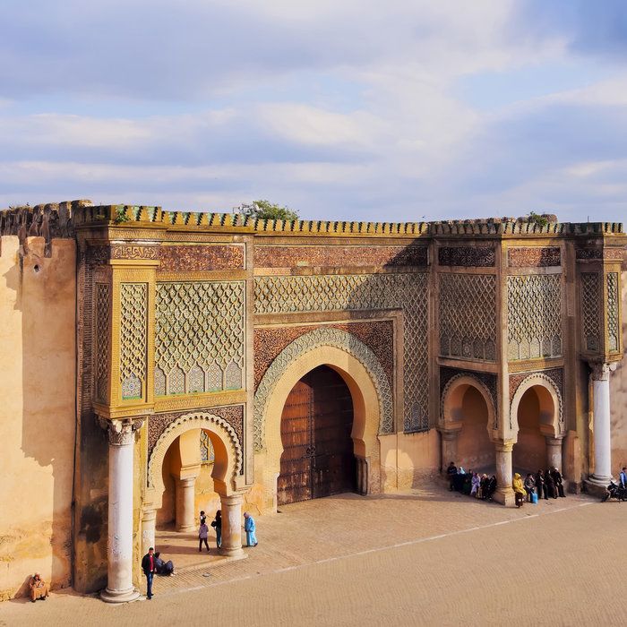Bab Mansour gate in Meknes by day with warm sandy tones and locals
