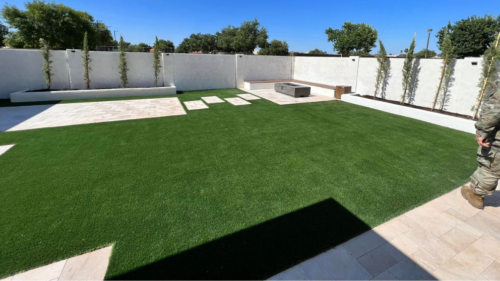 Backyard turf lawn with raised planter beds, bench, and paver walkway
