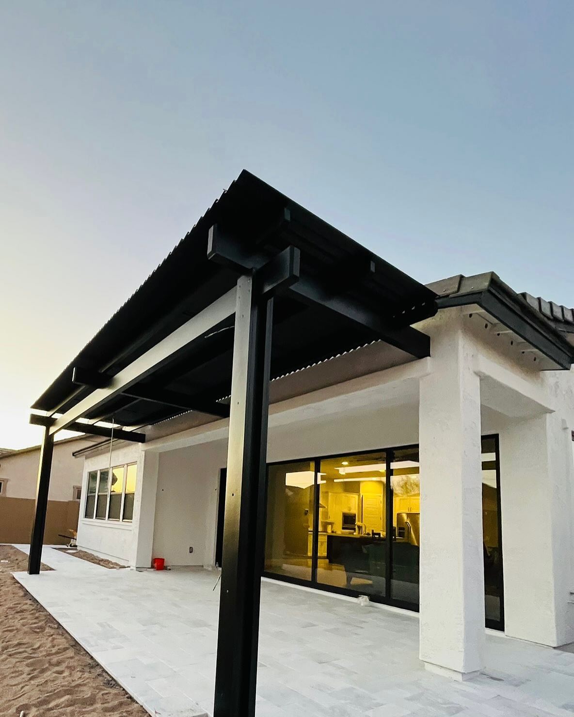Modern black steel patio cover attached to a white stucco home
