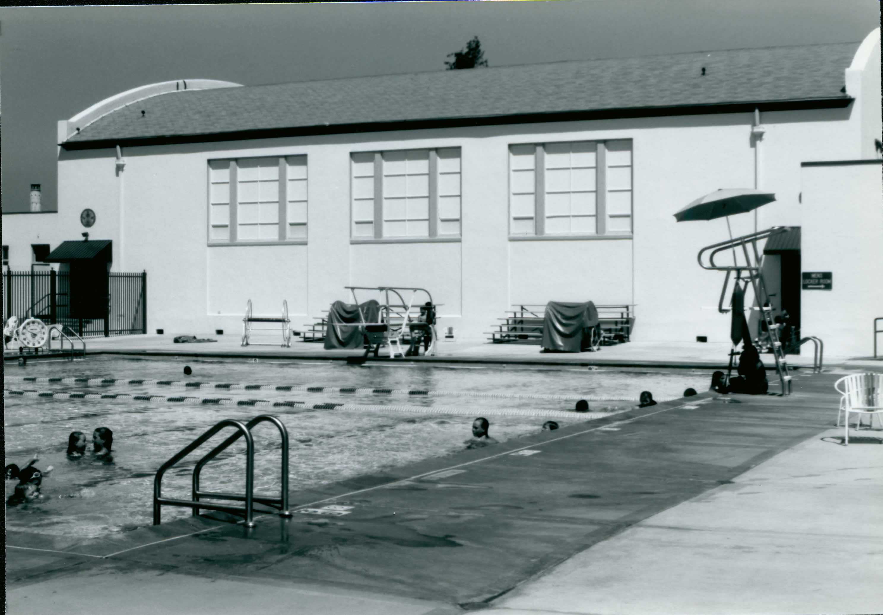 Swimmers in the Campbell pool beside the original pool building and diving board.