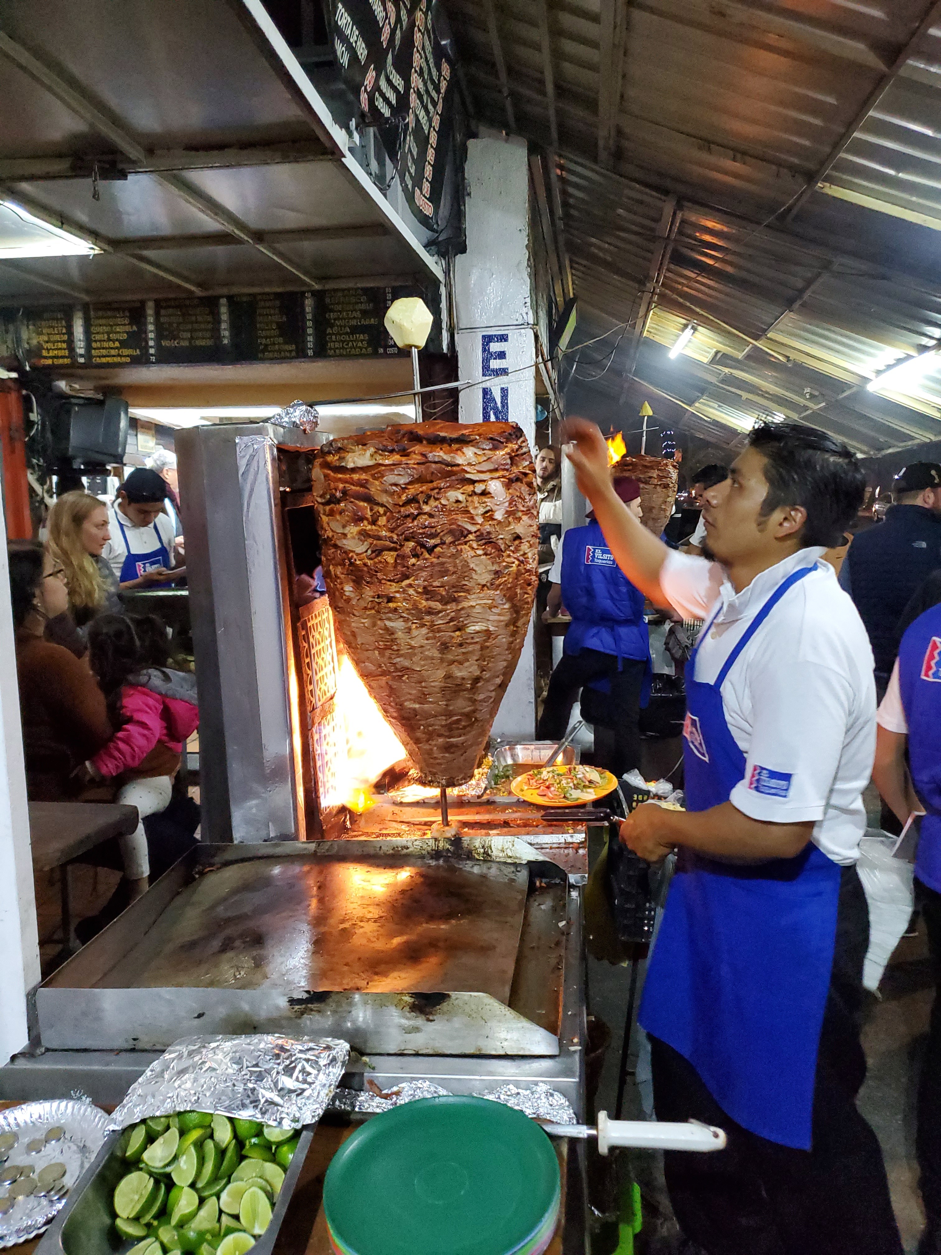 Taquero carving an al pastor trompo topped with pineapple at a late-night Narvarte taqueria, Mexico City