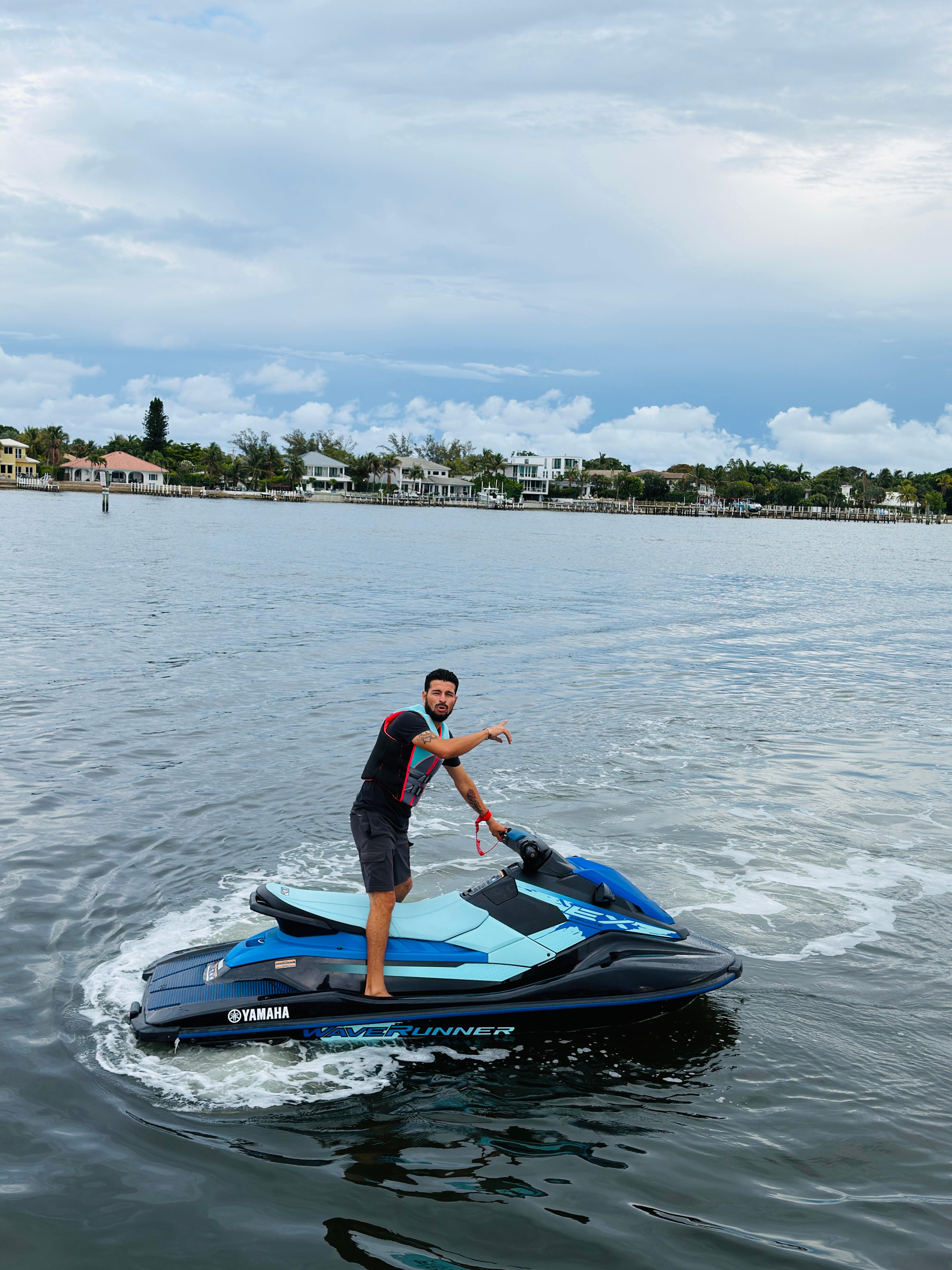Man standing on Yamaha WaveRunner in Palm Beach waterway with luxury estates behind