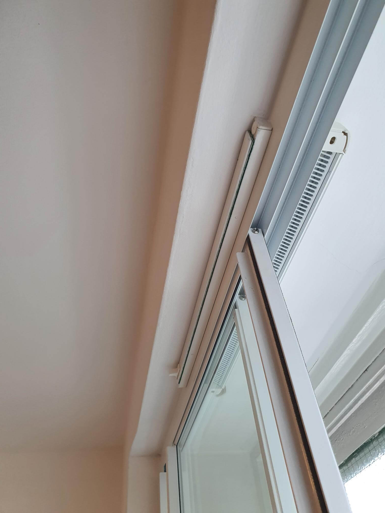 Close-up detail of secondary glazing aluminium frame with trickle vent and hinged opening mechanism