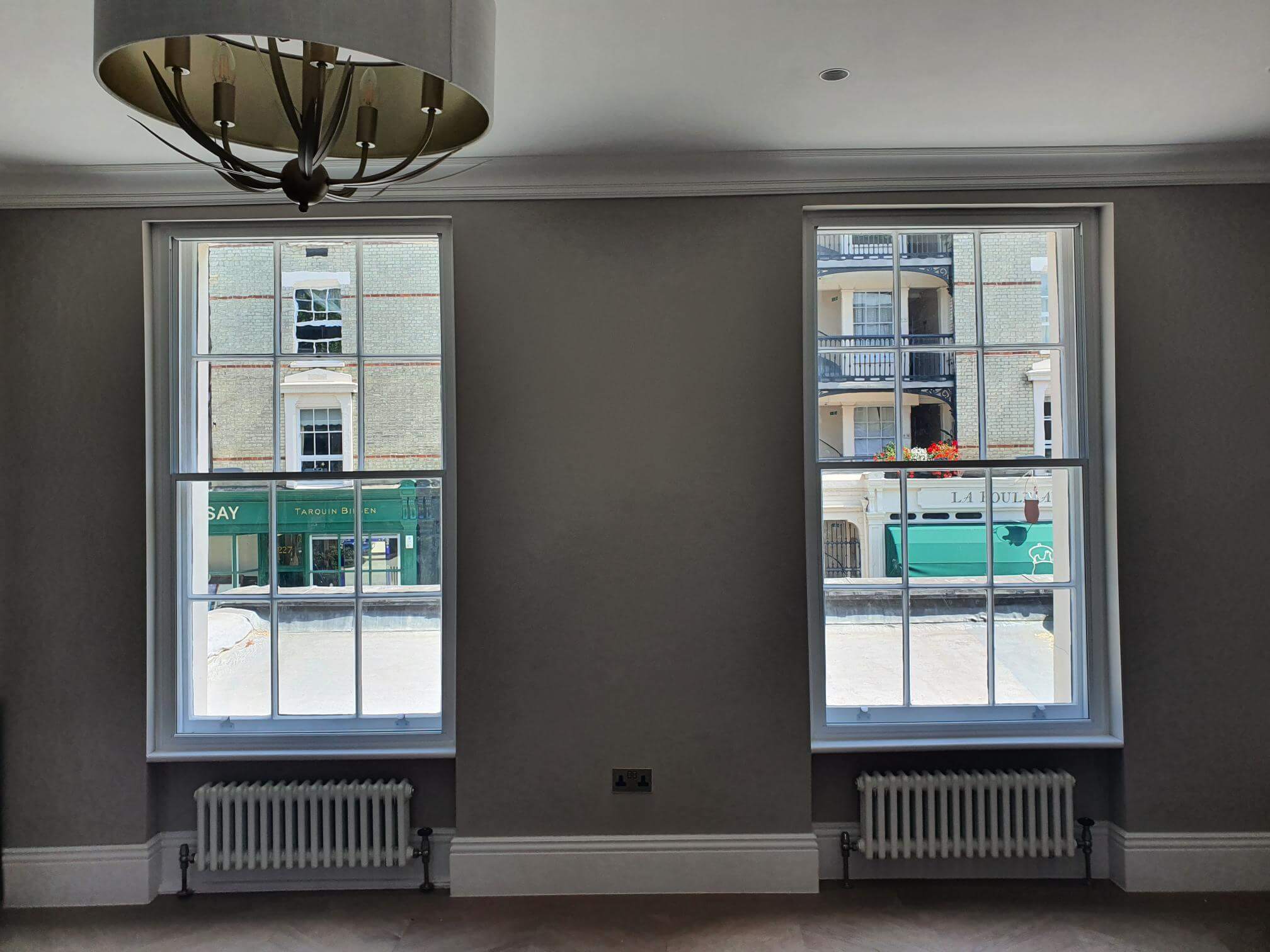 Two tall sash windows with secondary glazing in elegant London Pimlico living room with period radiators and chandelier