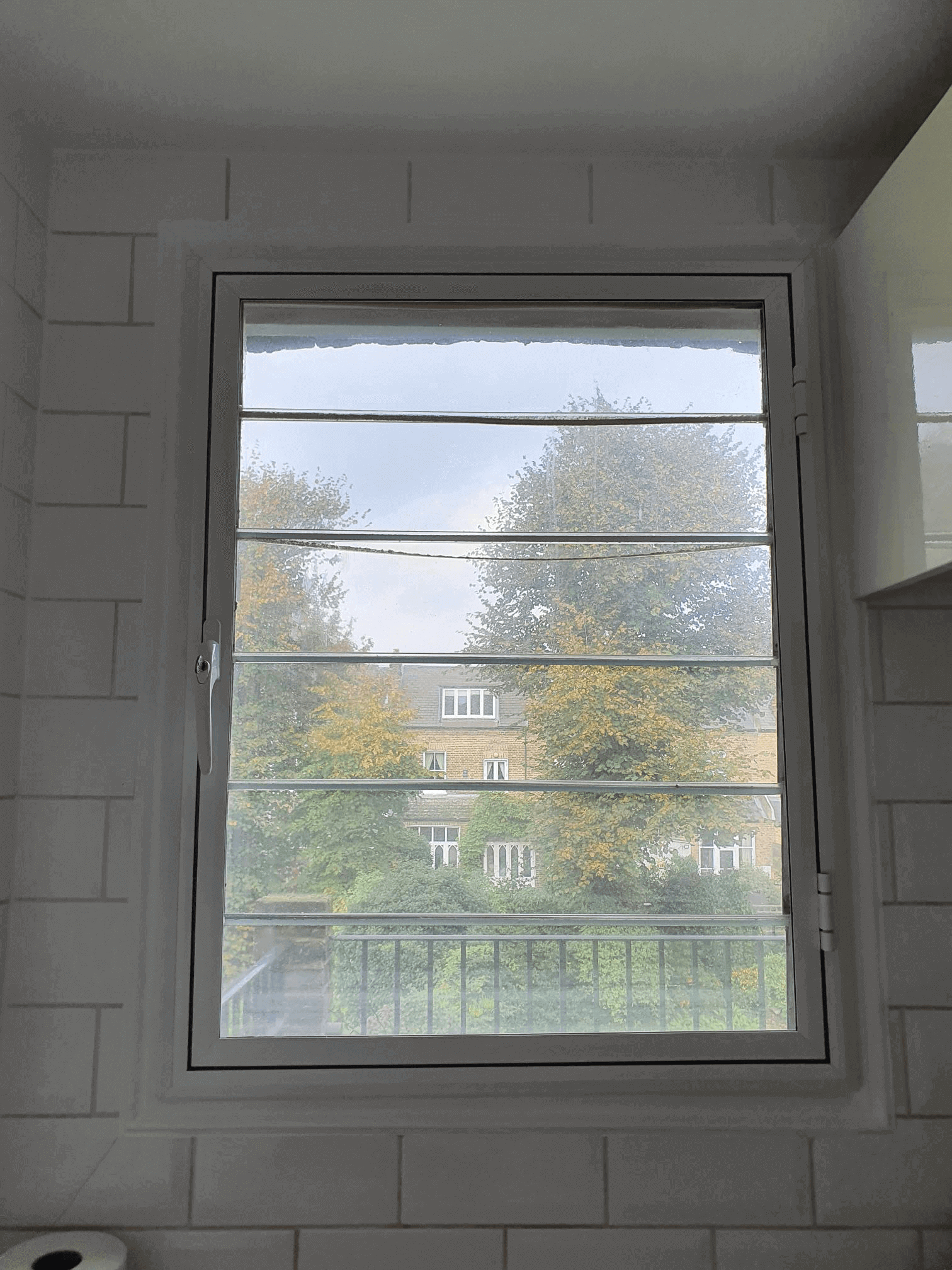 Casement window with secondary glazing in white-tiled London Putney bathroom overlooking garden