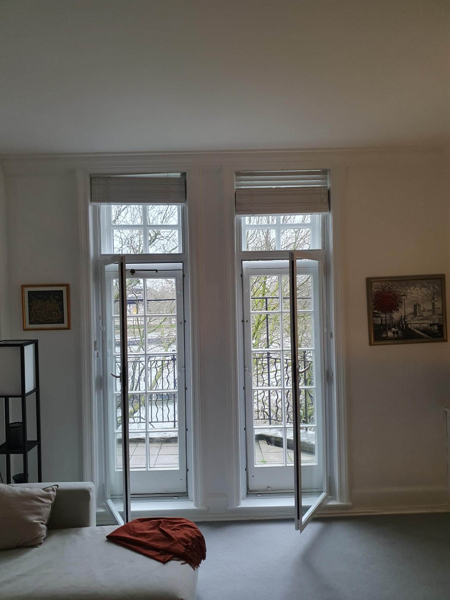 Two tall French doors with hinged secondary glazing panels open in London Chelsea Embankment living room with balcony views