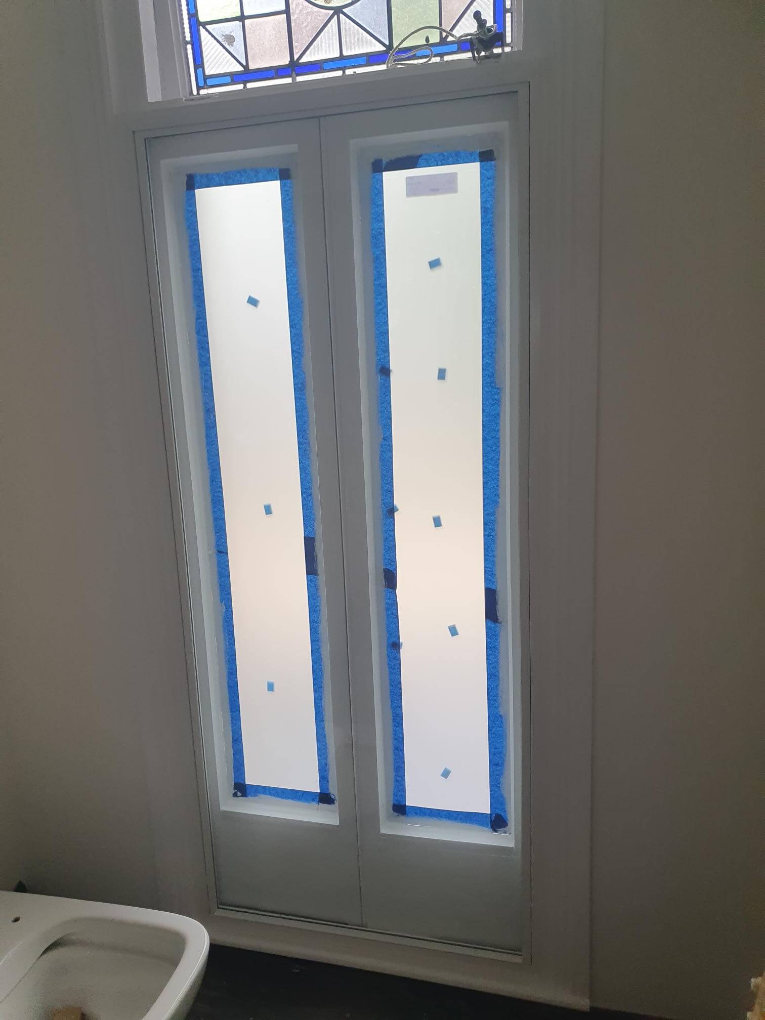 Bathroom frosted secondary glazing panels with original Victorian stained glass fanlight preserved in London Hampstead period property
