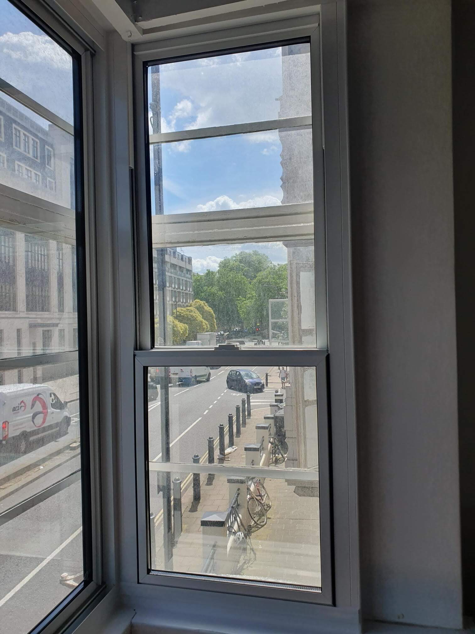 Commercial secondary glazing window in London Bloomsbury office overlooking busy street with cyclists and pedestrians