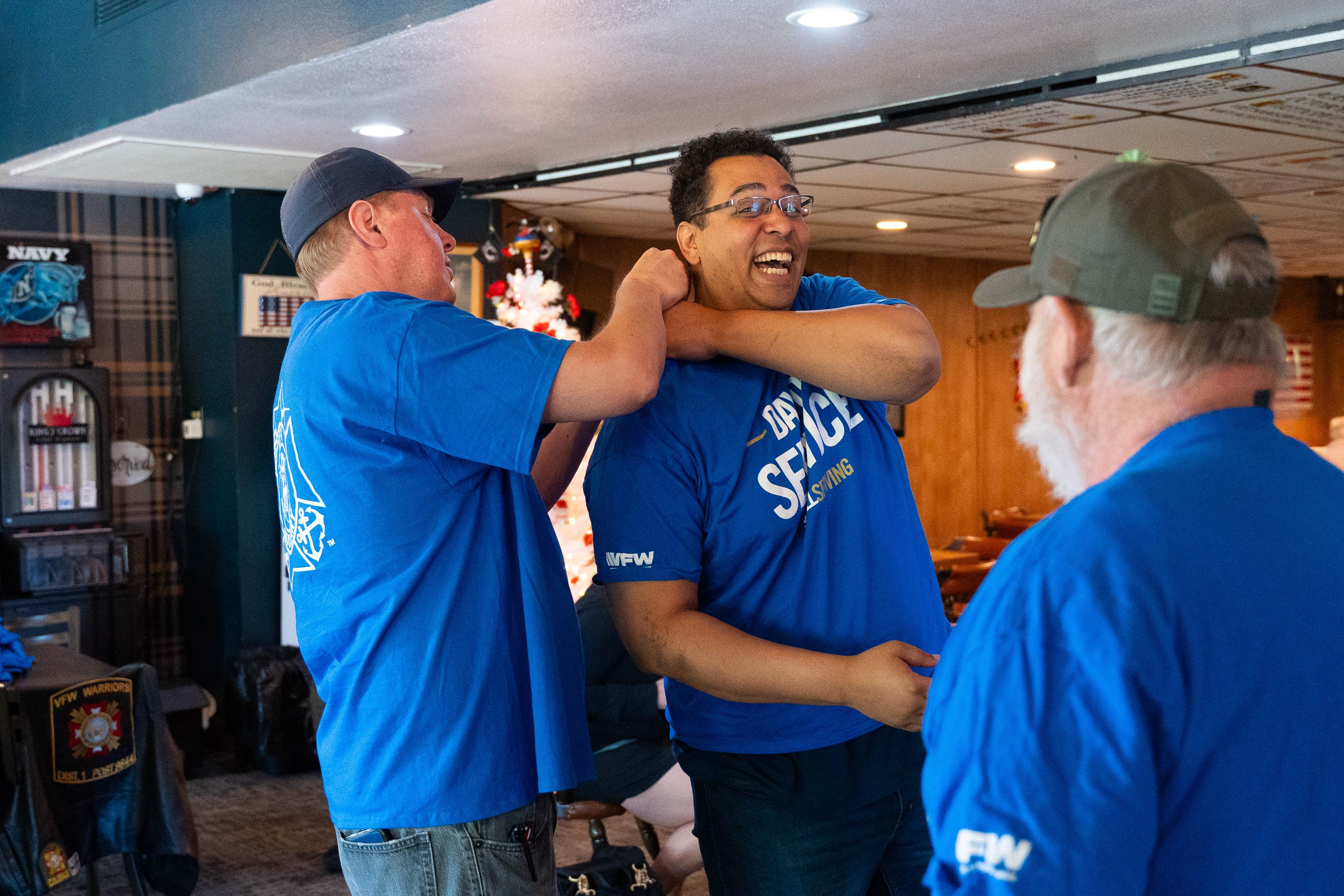 Veterans laughing together inside a VFW Post with military memorabilia on walls