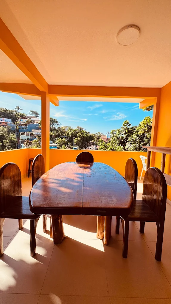 Varanda da pousada com mesa de madeira e vista para Morro de São Paulo