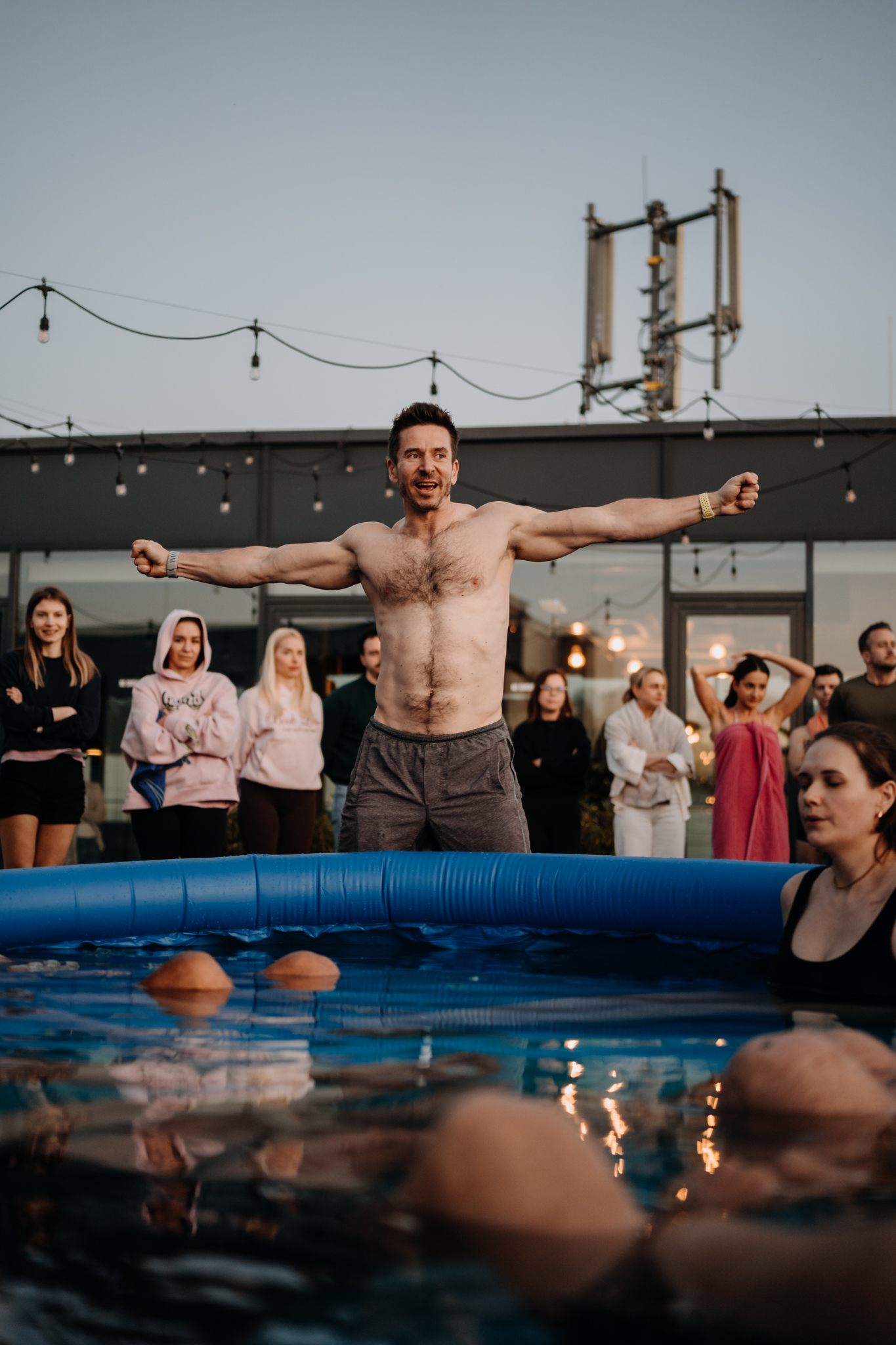 Facilitator with arms wide standing beside a cold plunge pool