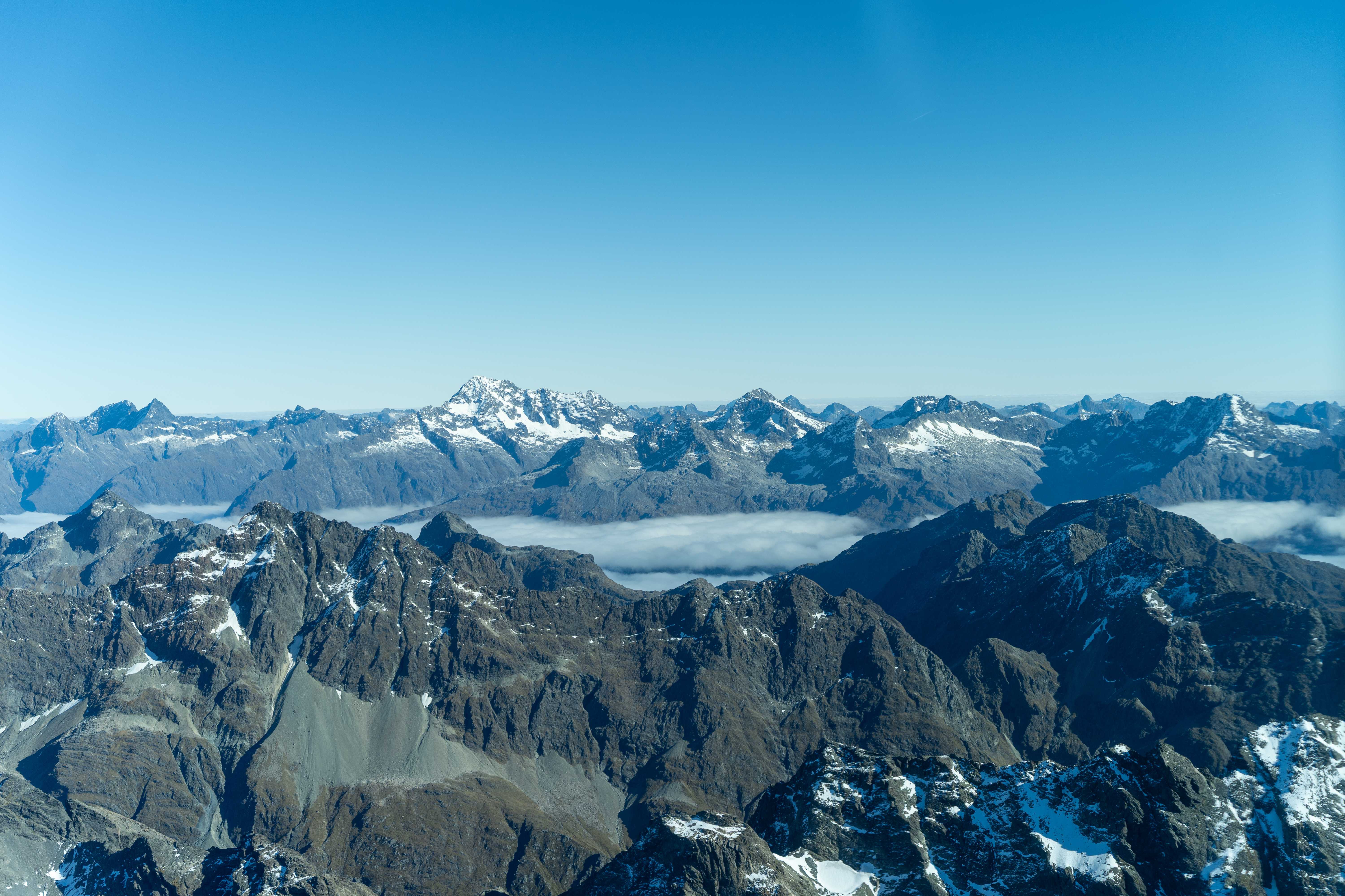 Aerial view of snow-capped mountain ranges above a sea of cloud