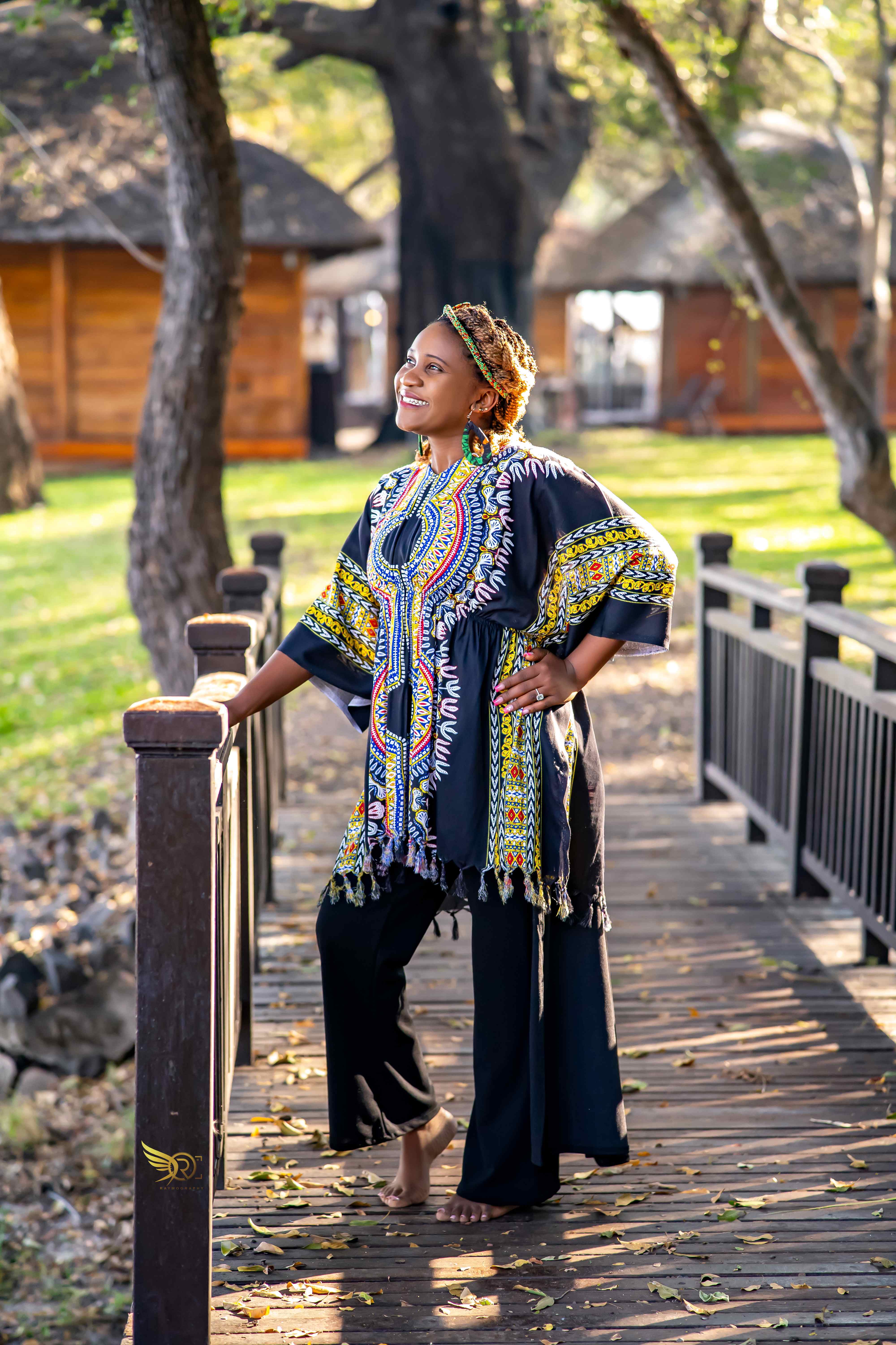 Tendai in traditional African print dress on wooden boardwalk with trees in background