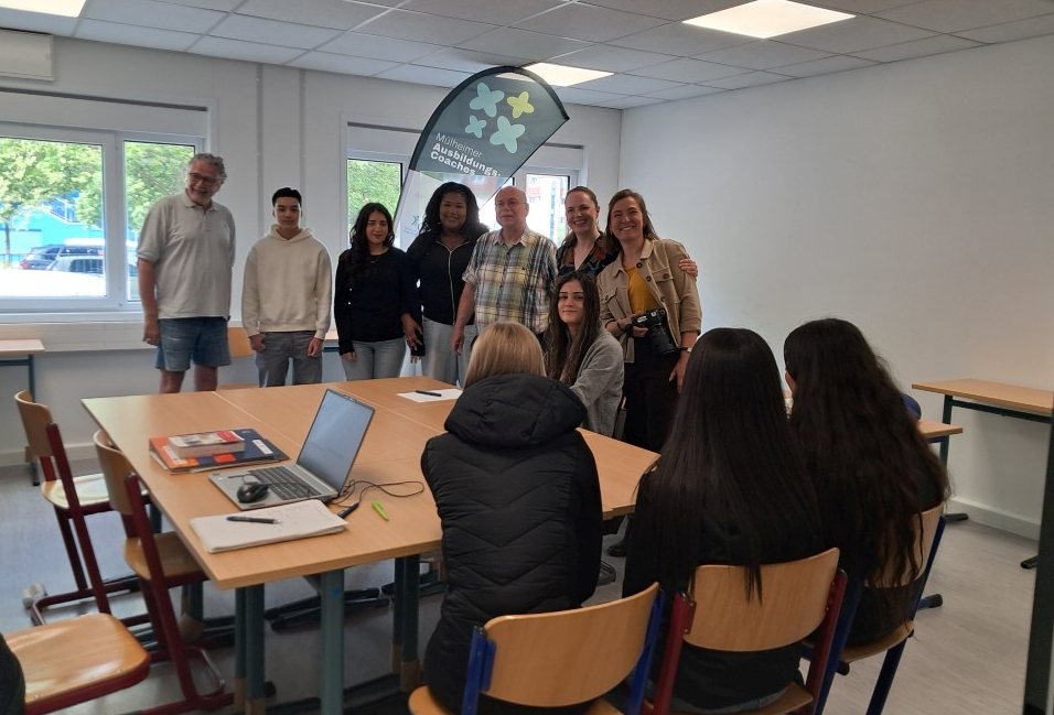 Gruppendiskussion mit Ausbildungscoaches und Jugendlichen um einen Konferenztisch
