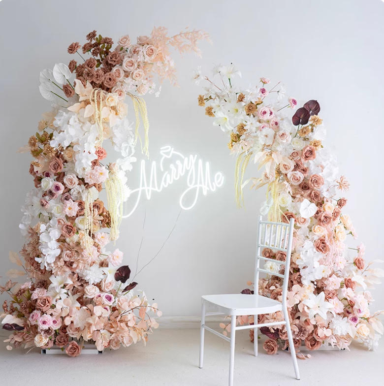 Blush and white circular floral arch with a Marry Me neon sign — full range of wedding arches for hire