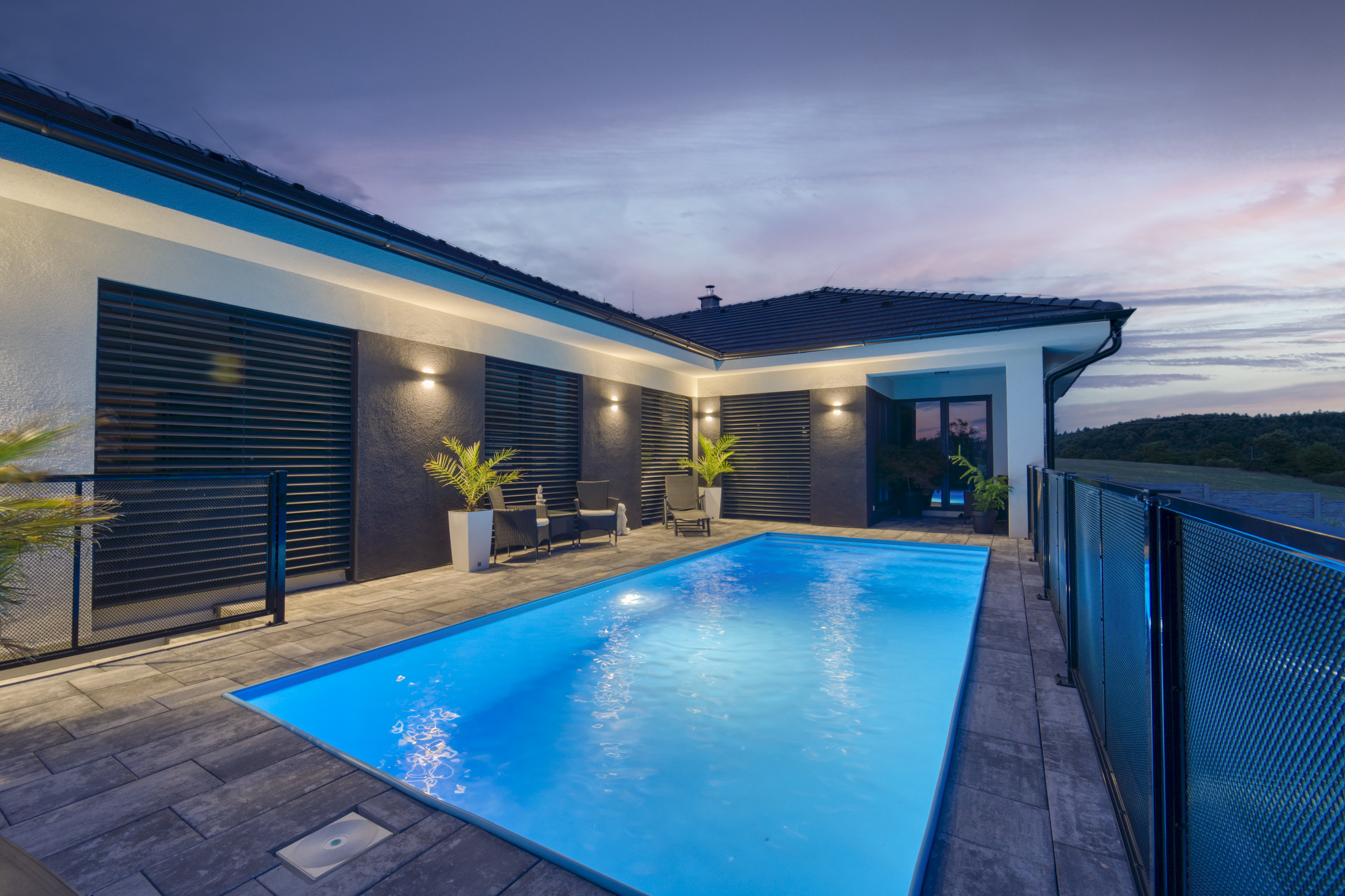 Modern house and illuminated pool at dusk