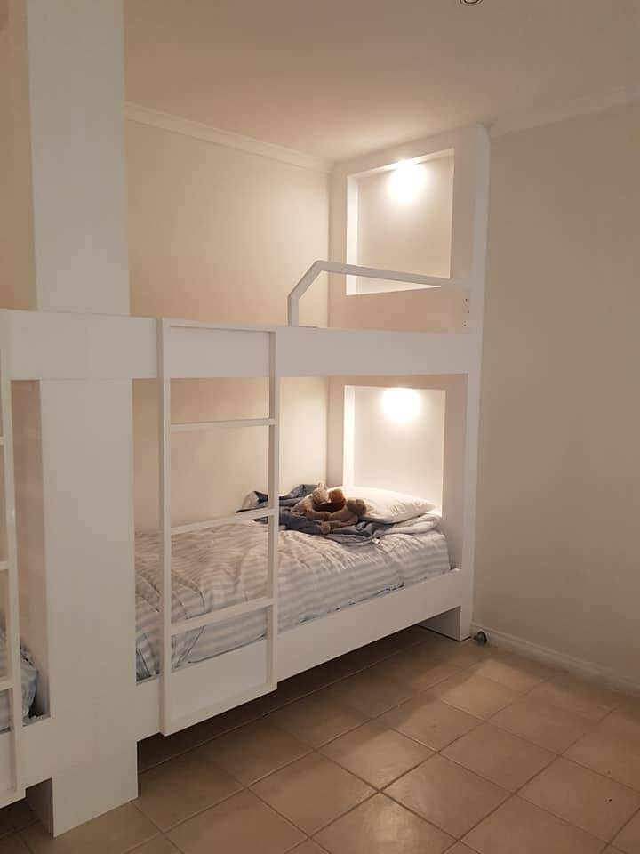 Custom built-in white bunk beds with integrated LED lighting and storage