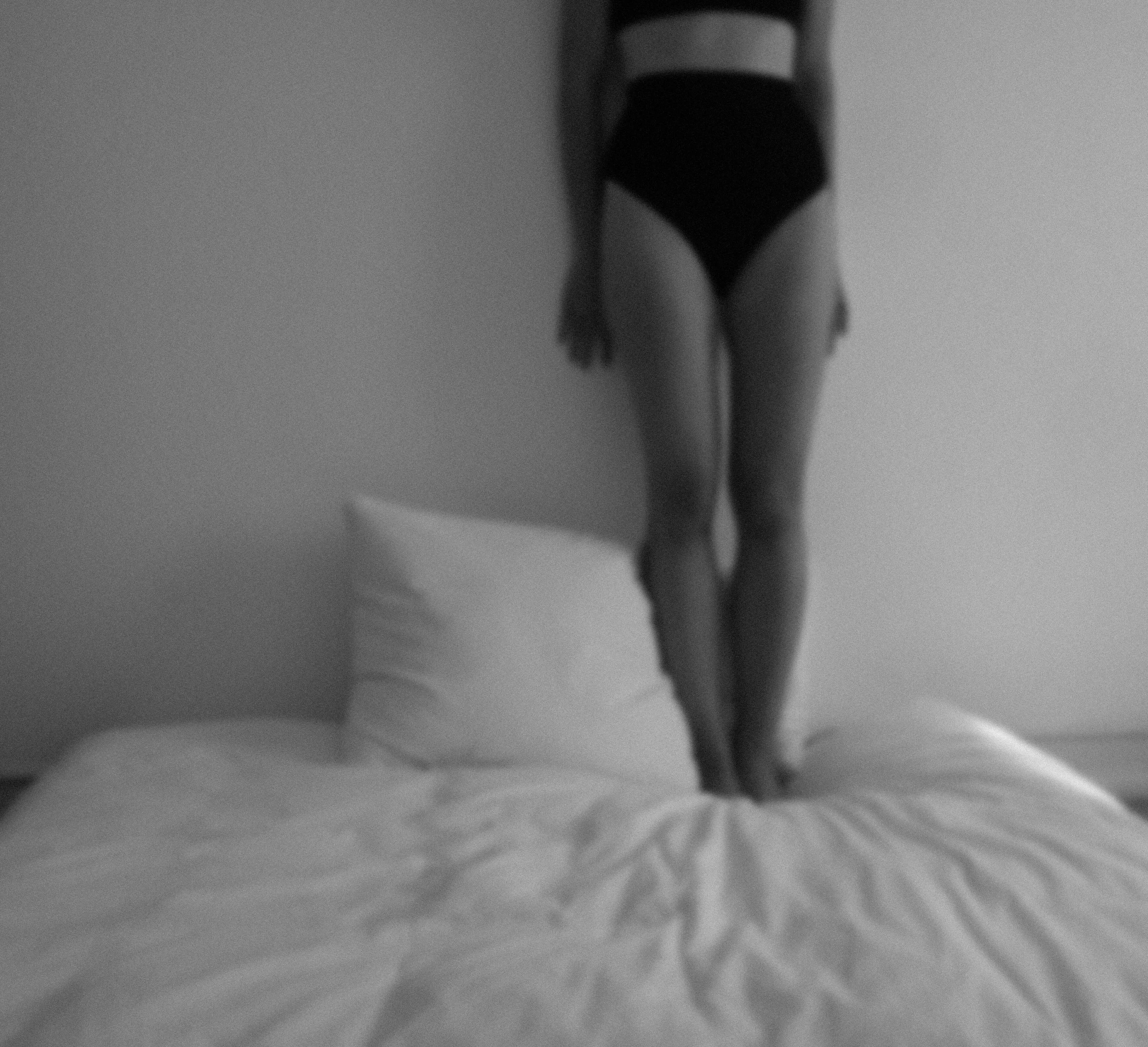 Black and white silhouette of a woman standing on a bed