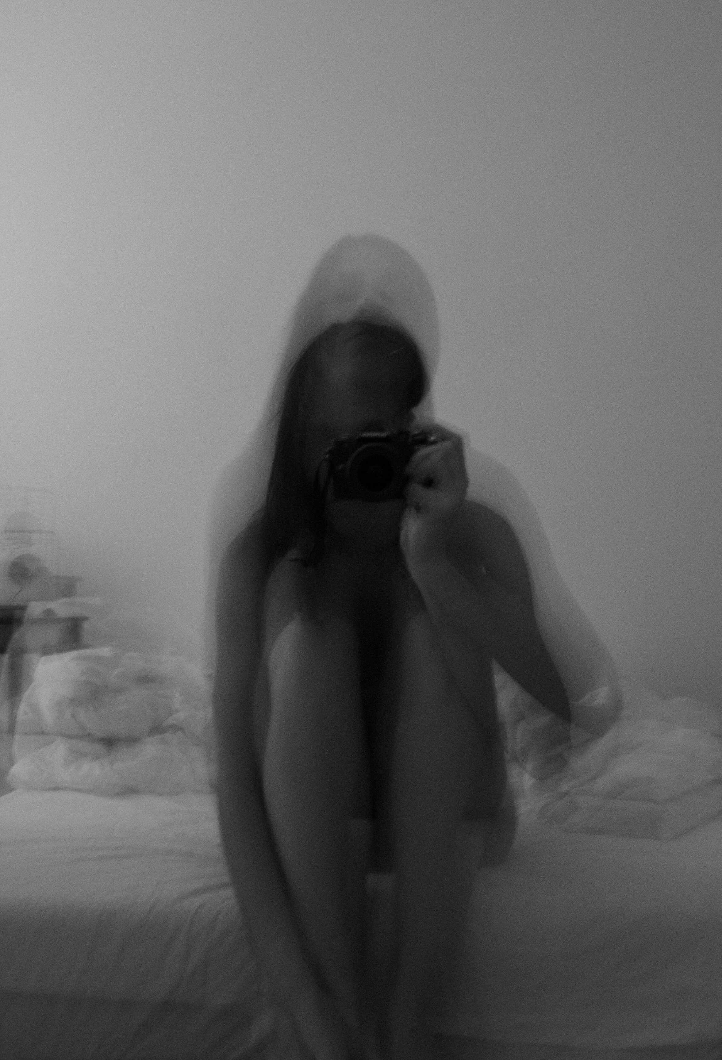 Blurred black and white image of a person taking a self-portrait with a camera