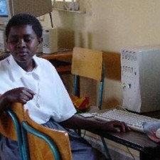 Teilnehmerin tippt auf einer Tastatur im Computerraum der Missionsschule