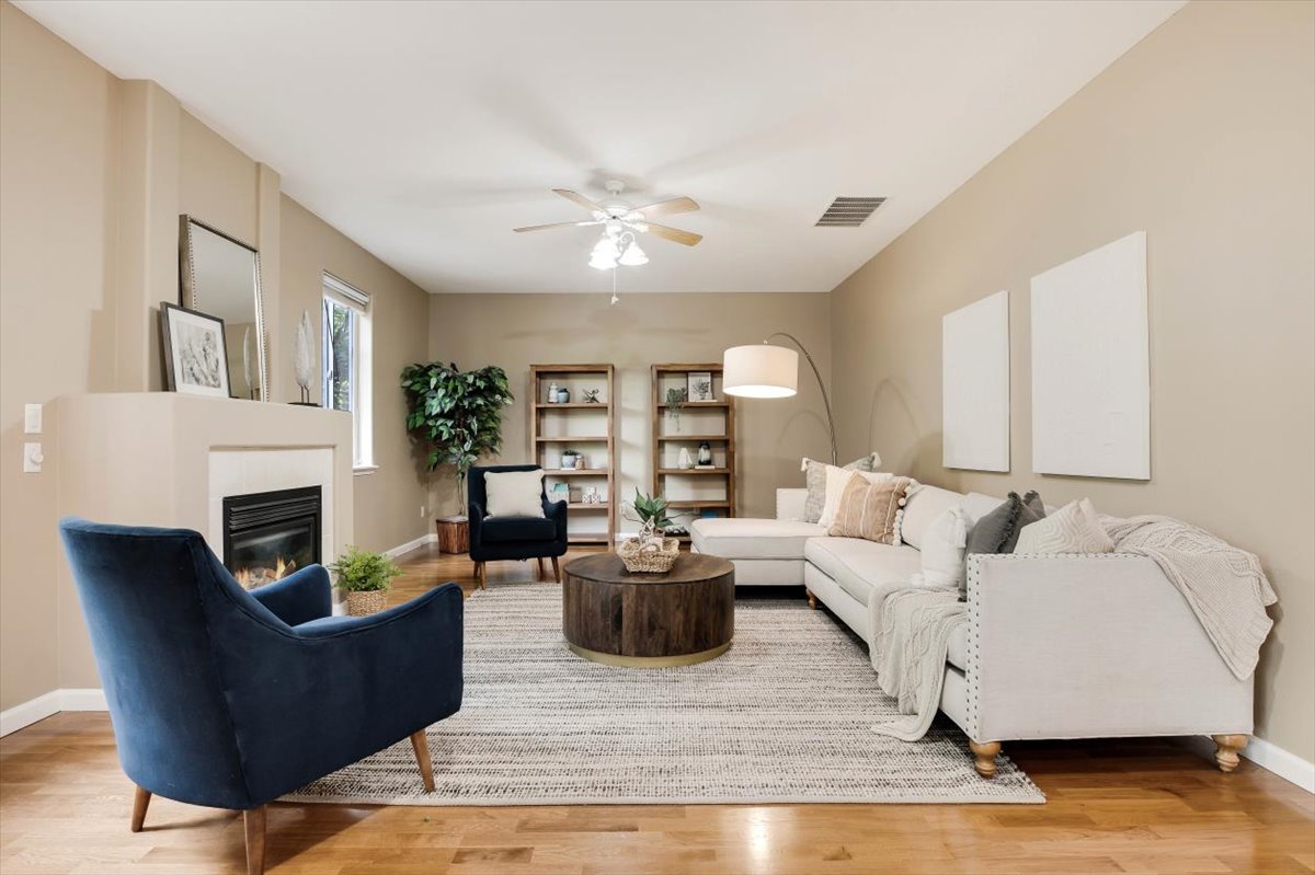 Professionally staged living room with beige sofa, blue accent chair, and warm lighting