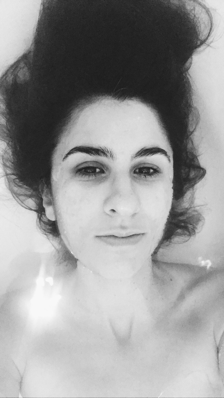 Black and white self-portrait of a woman with curly hair in water, eyes open