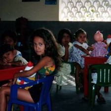 Mädchen an bunten Stühlen, Puppe auf dem Tisch