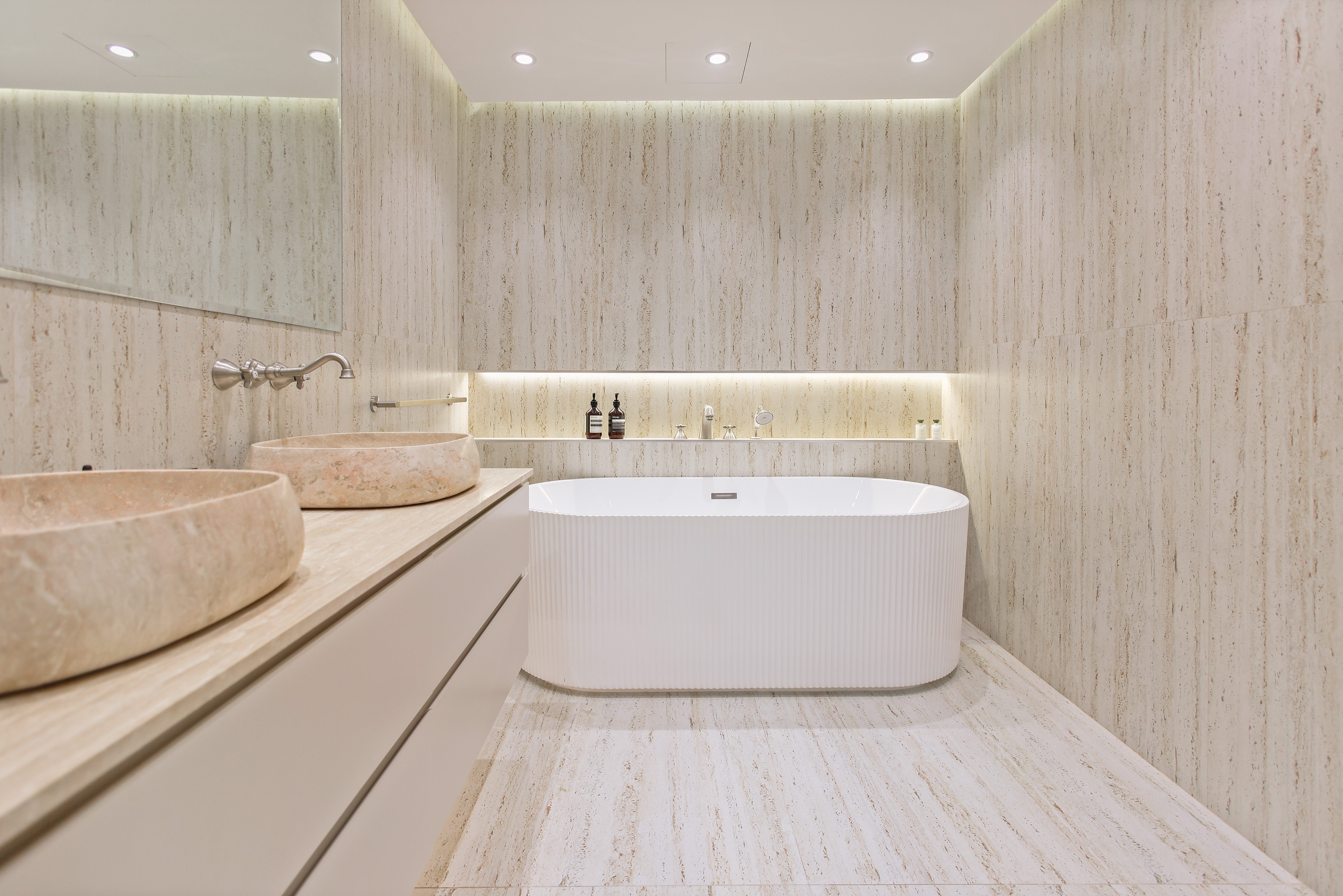 Luxurious spa bathroom with travertine walls and freestanding fluted tub