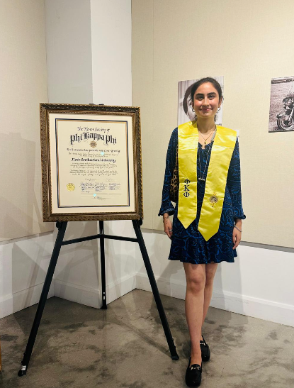 Vanya beside a certificate recognizing her work