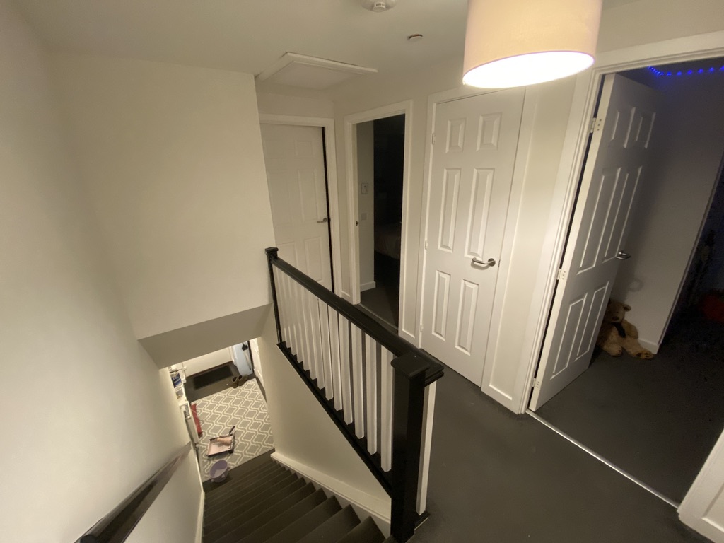 Bright landing with crisp white walls and dark charcoal handrail contrasting white spindles