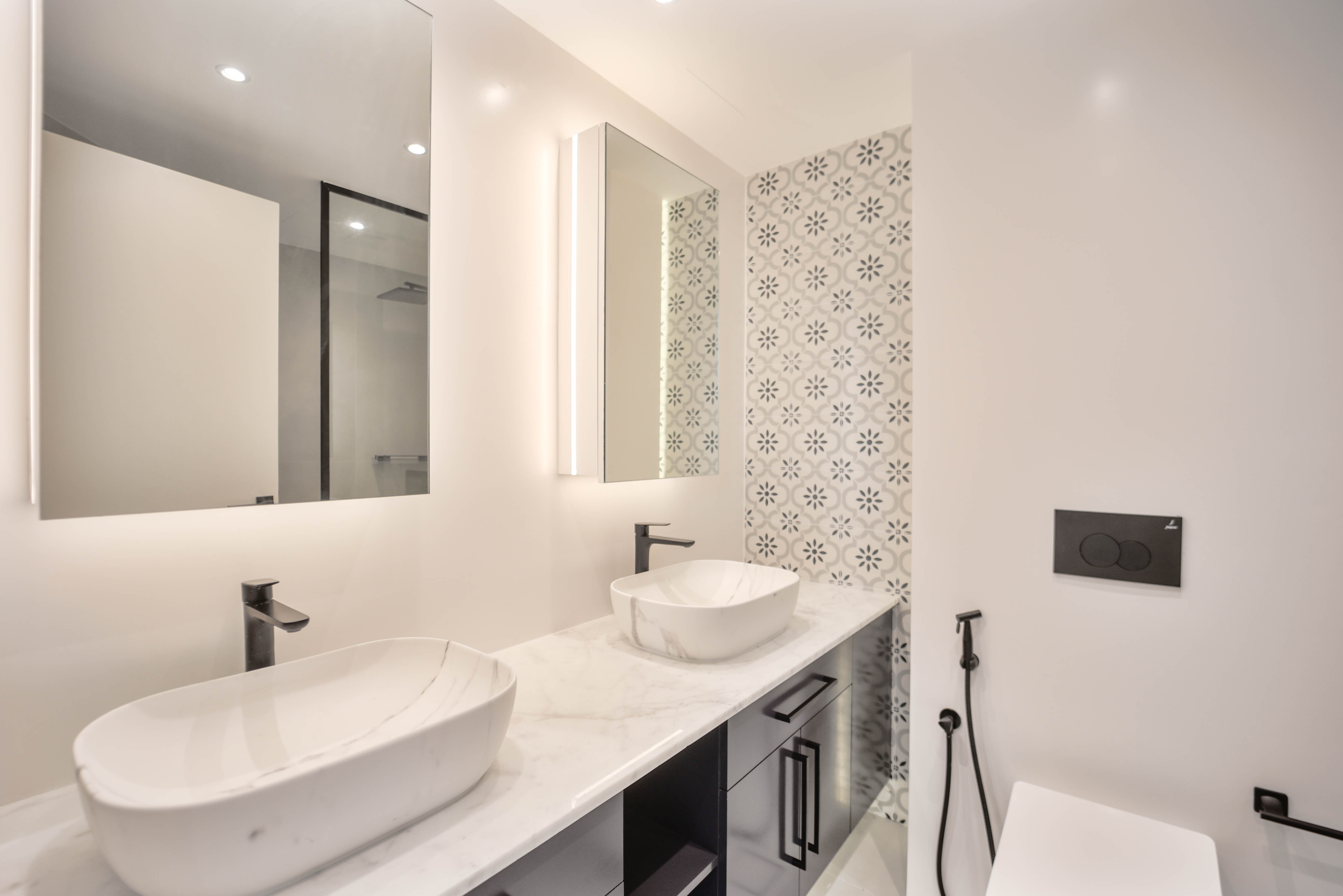 Bathroom with double vessel sinks and patterned tile accent wall