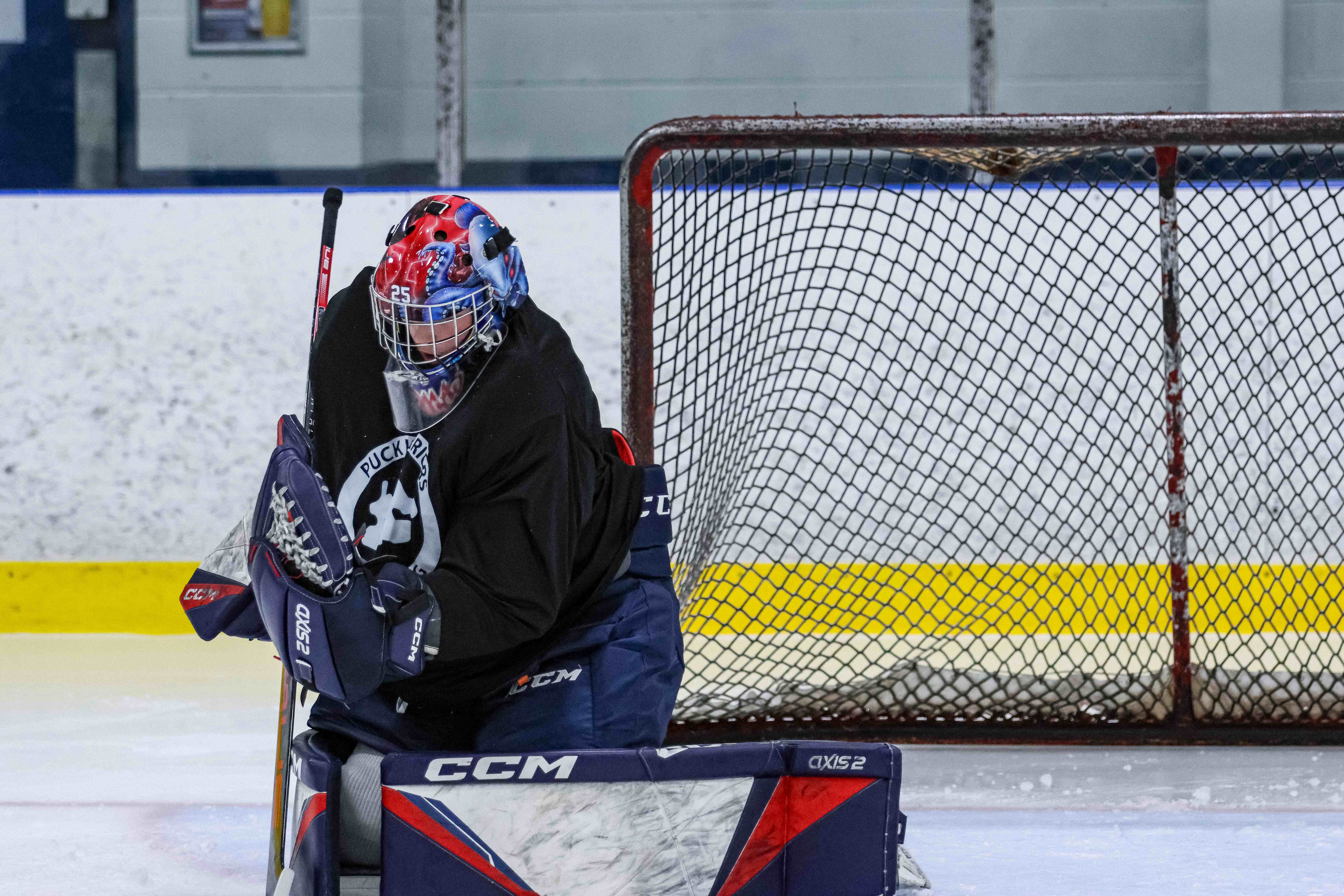 Young goalie in a red helmet making a pad save