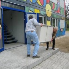 Zwei Personen tragen Möbel in den Container