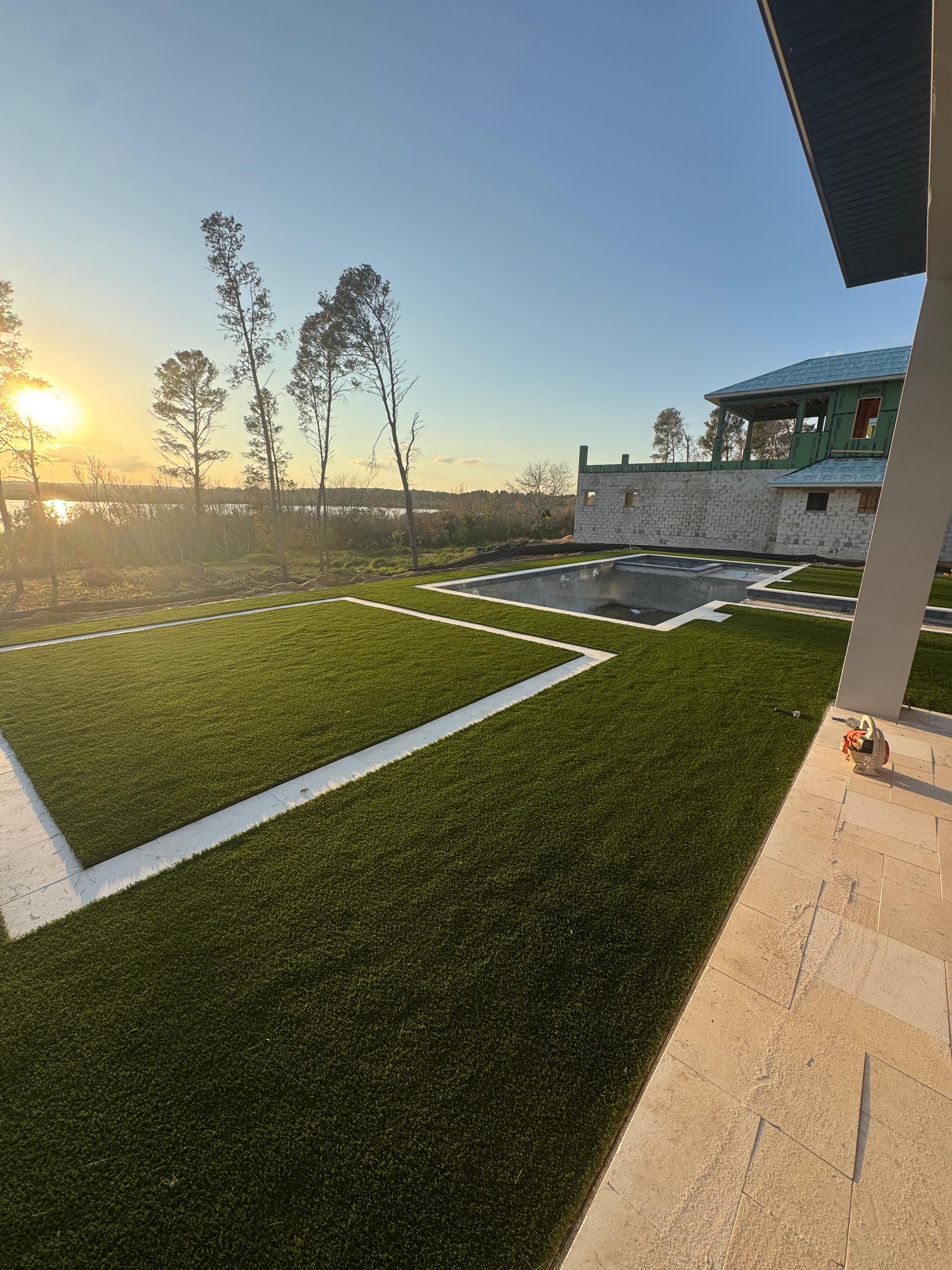 Área externa com gramado artificial e piscina