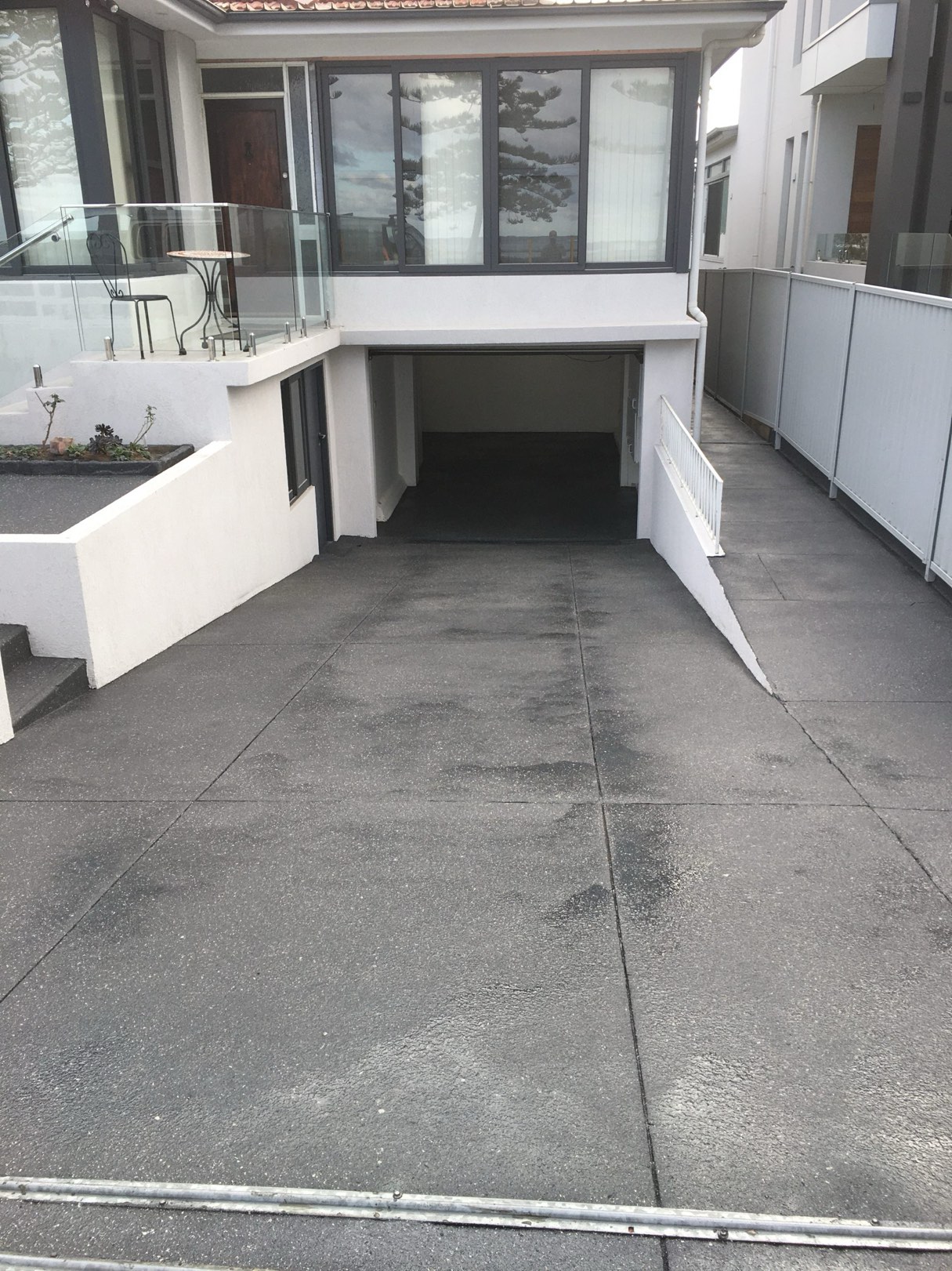 Same driveway resurfaced with a clean charcoal Spray Crete finish leading to an underground garage