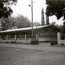 Straßenansicht des Schulgebäudes hinter einem Zaun