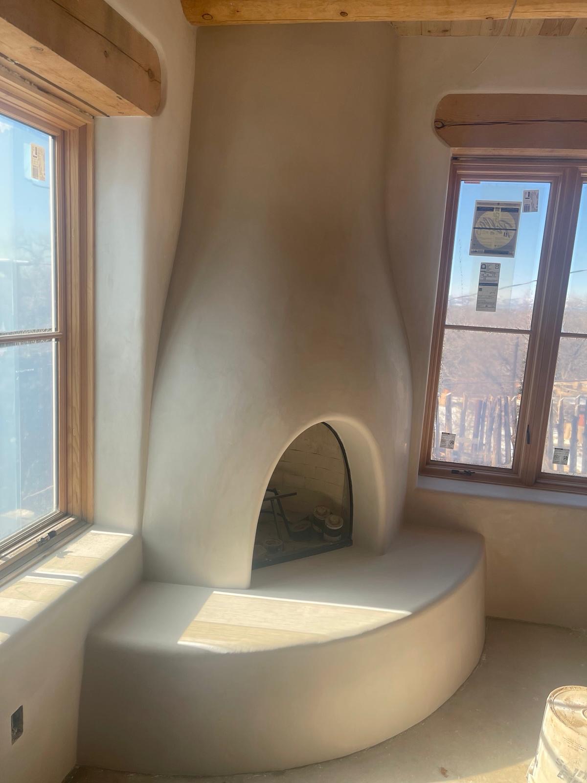 Corner kiva fireplace with smooth stucco finish and wood beam ceiling