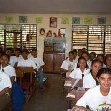 Voller Klassenraum mit Schülerinnen und Schülern in weißen Uniformen