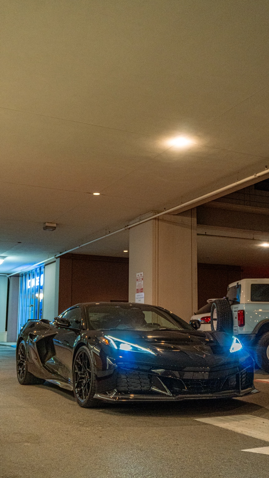 Black C8 Corvette in parking garage with dramatic blue ambient lighting