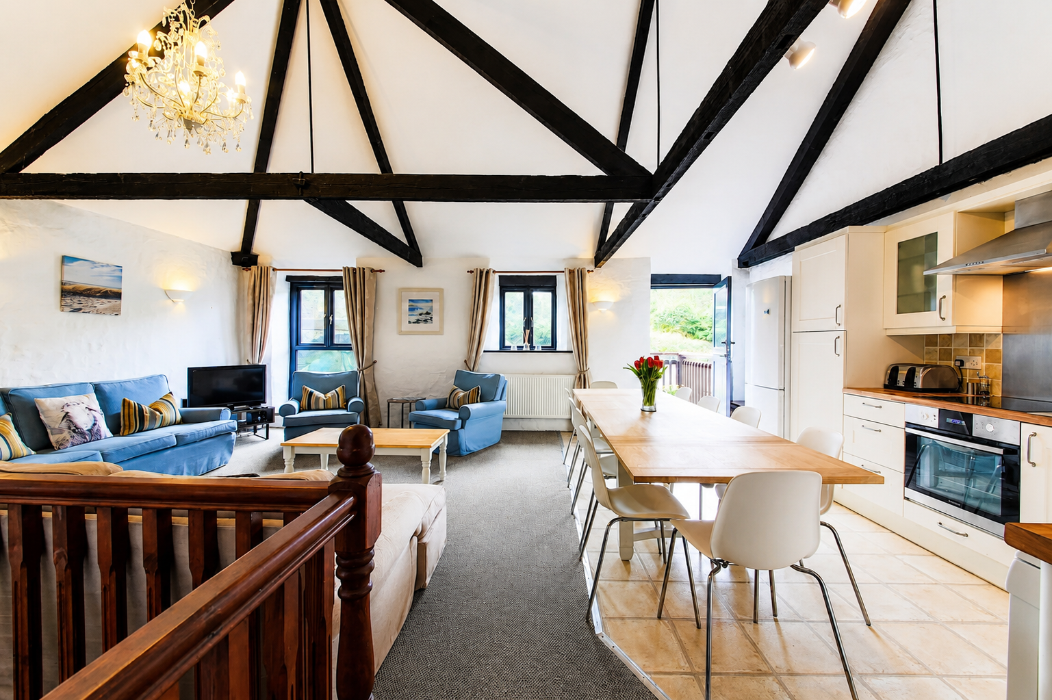 Grand open-plan living and dining room with dramatic black vaulted timber beams and chandelier