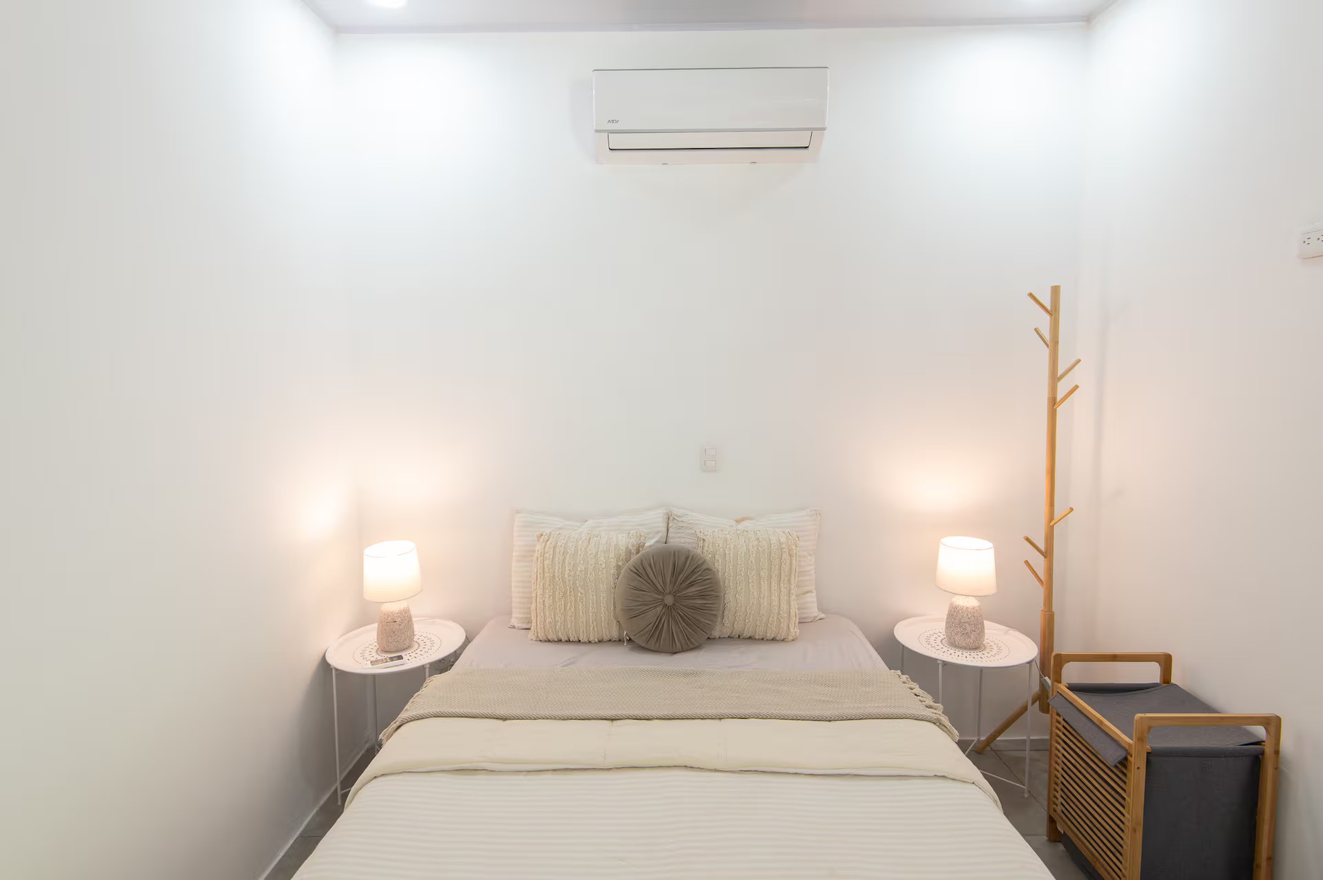 Bedroom with queen bed, air conditioning, bedside lamps and clothing rack