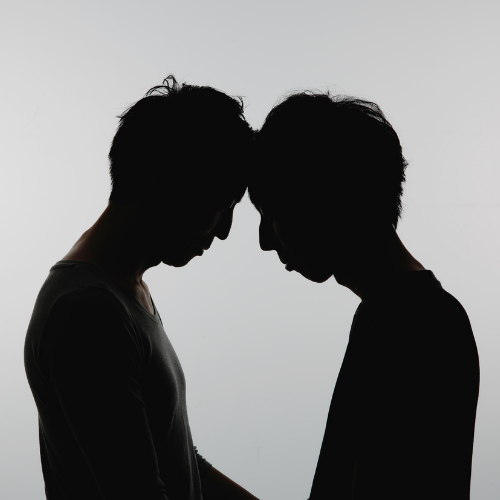 Two people in silhouette with foreheads touching
