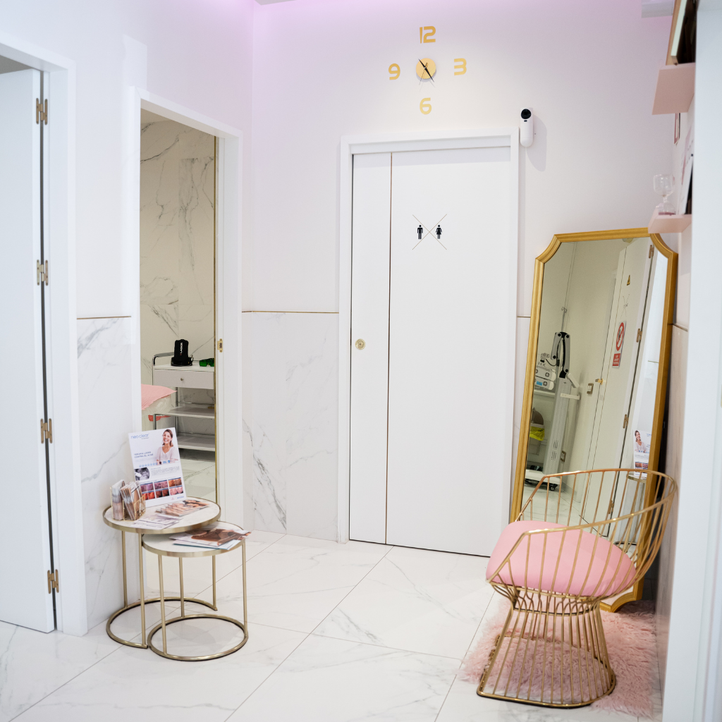 Pasillo de Lum Clinic con espejo dorado y silla rosa