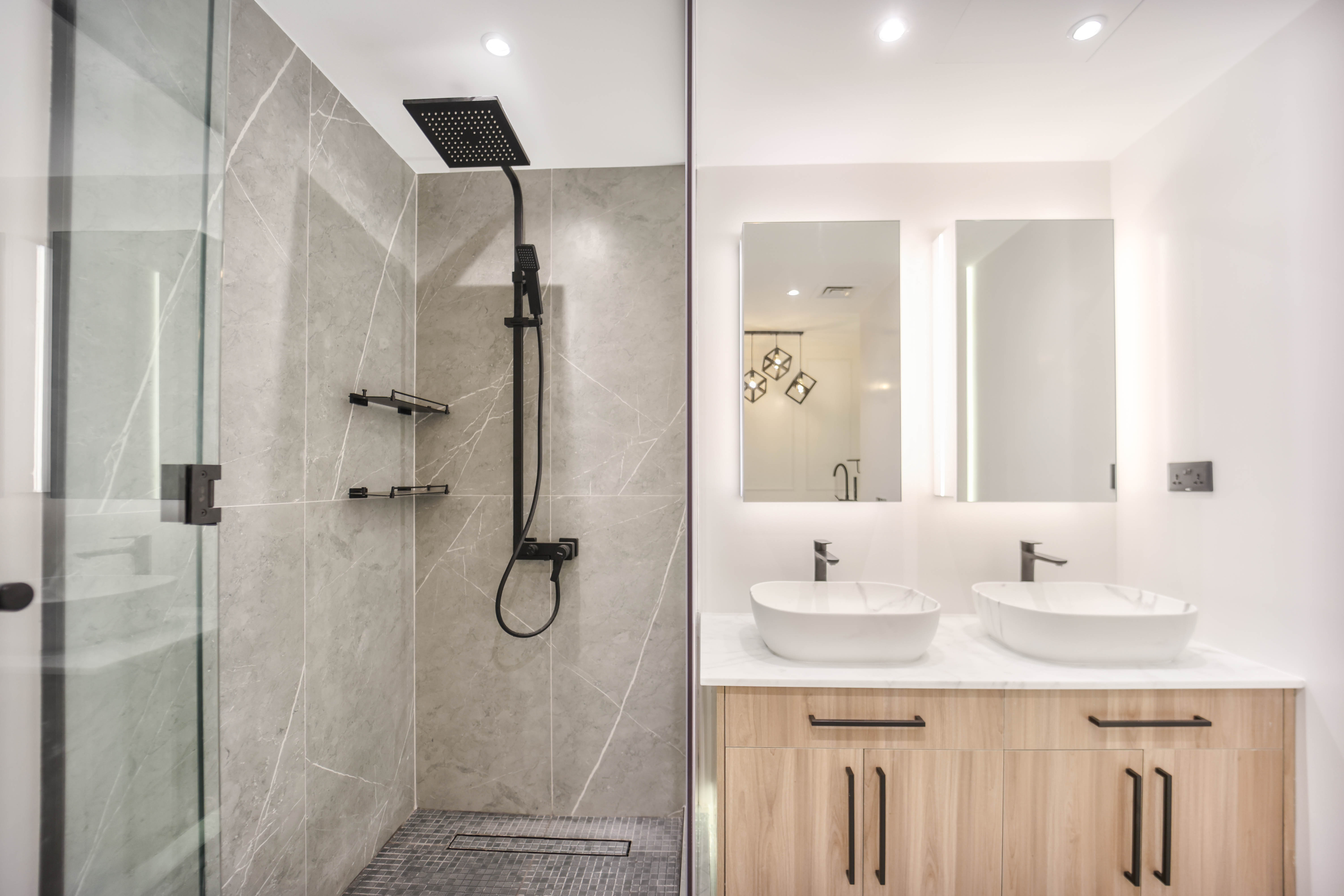 Modern bathroom with gray marble shower and double vessel sinks