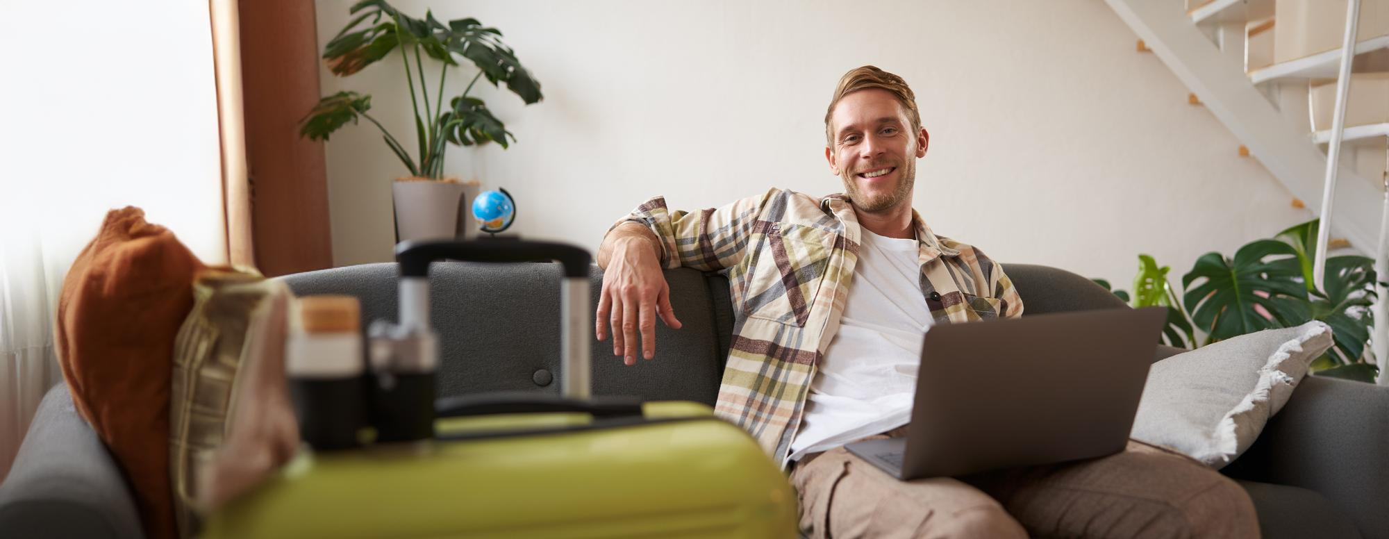 A smiling entrepreneur working on a laptop from a comfortable living room