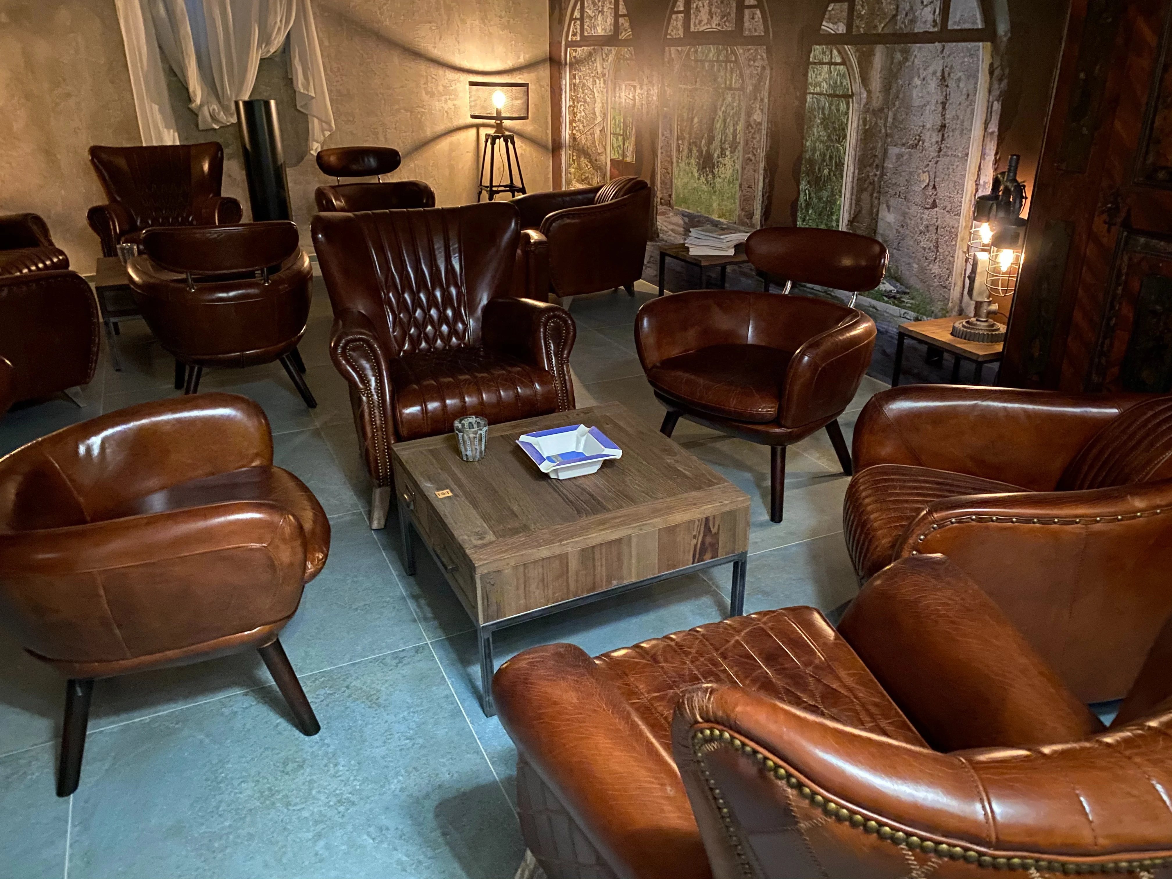 Sitzbereich der Lounge mit Ledersesseln vor gemalter Fensterkulisse