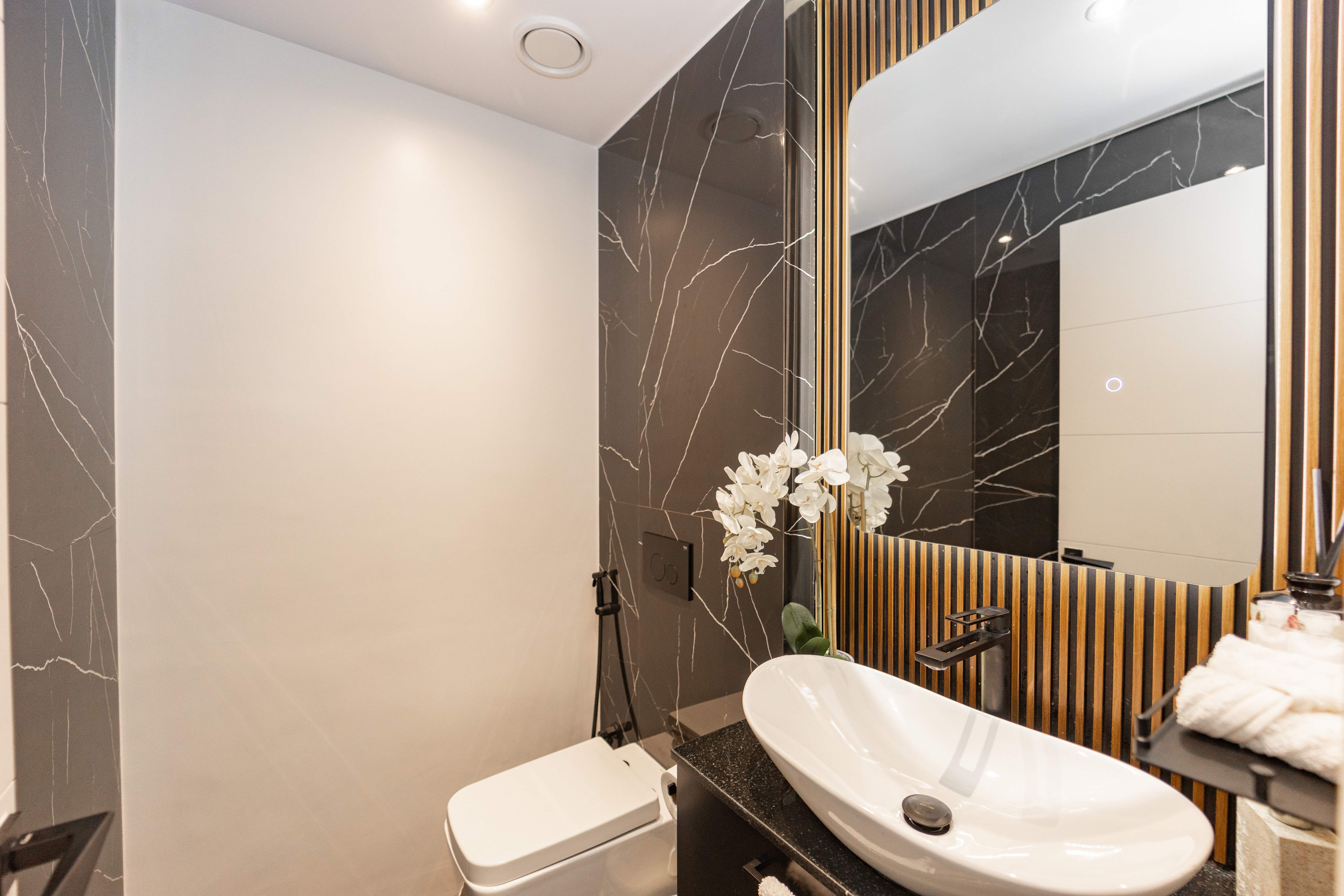 Powder room with dark marble walls and wood slat accent