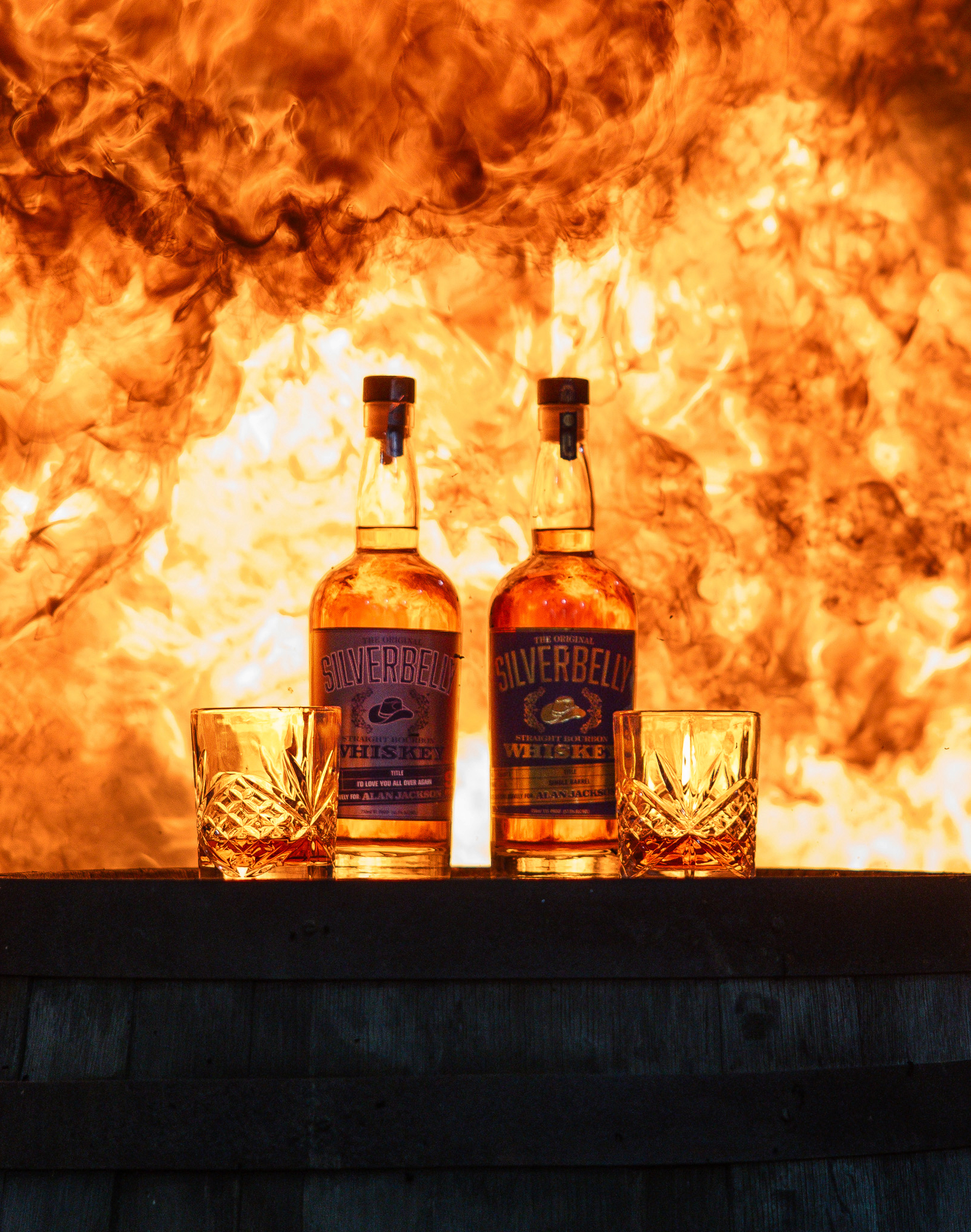 Silverbelly Whiskey bottles with crystal glasses backlit by fire